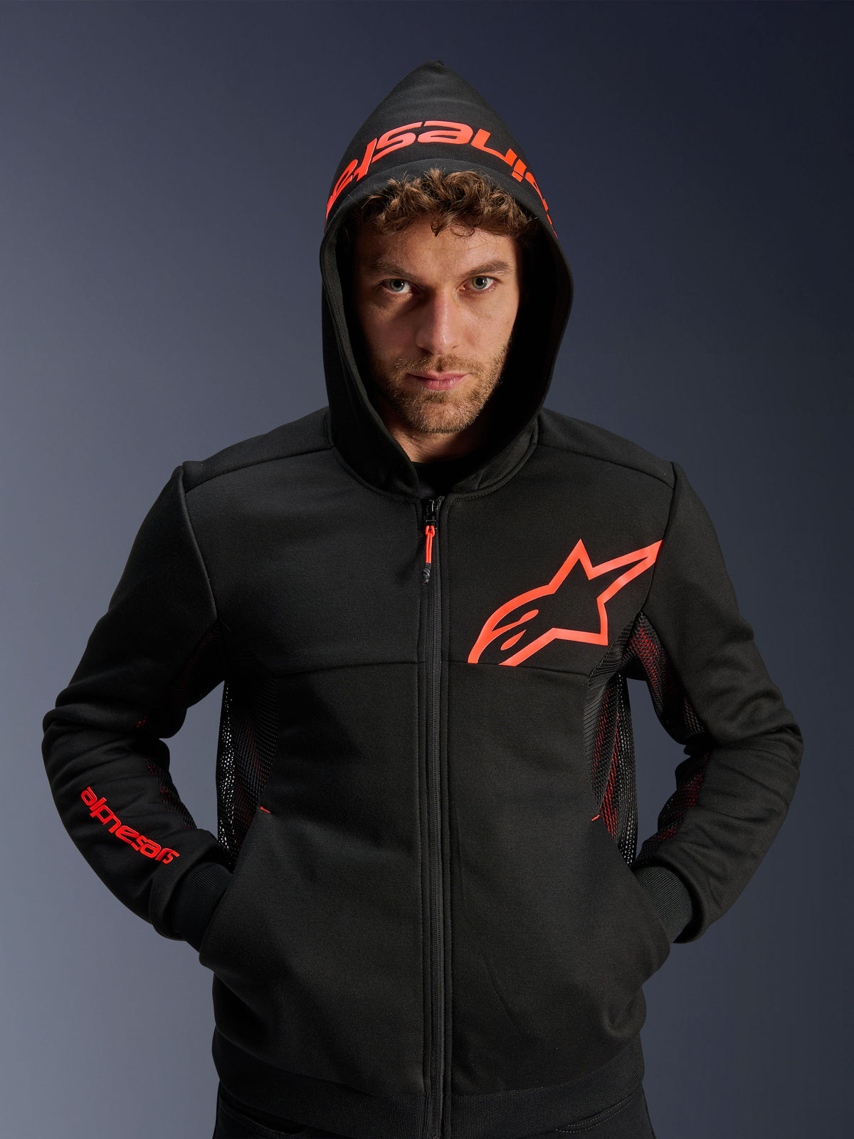 Alpinestars Chrome Air Sport Hoodie, negro y rojo fluo, sudadera urbana para motocicleta con paneles de ventilación de malla, logotipo Astar rojo en el pecho y capucha con marca, prenda de conducción casual para entornos urbanos.