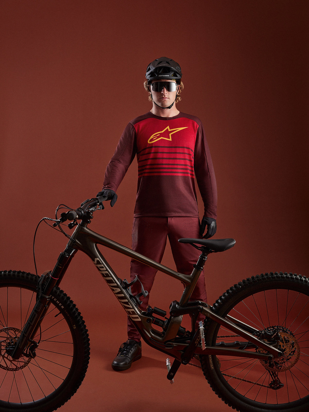 Jersey A-Dura Elite 2.0 burdeos de manga larga para MTB, con panel rojo, logo amarillo y bicicleta de montaña.