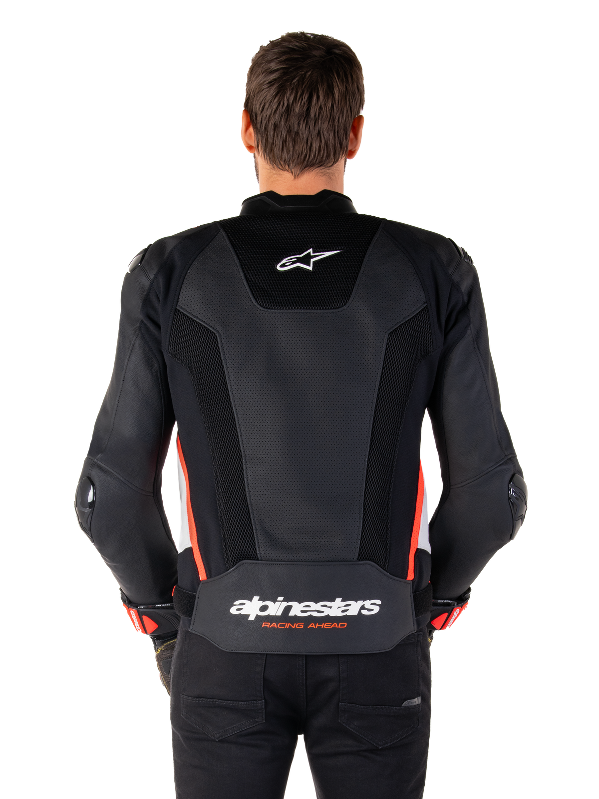 Vista posterior de una persona con la chaqueta de cuero Alpinestars Missile V3 Airflow en color Negro Blanco Rojo Fluo, con extensos paneles de cuero perforado para ventilación, un pequeño logo de Alpinestars en la parte superior de la espalda y la inscripción 'alpinestars RACING AHEAD' en la parte inferior de la cintura.