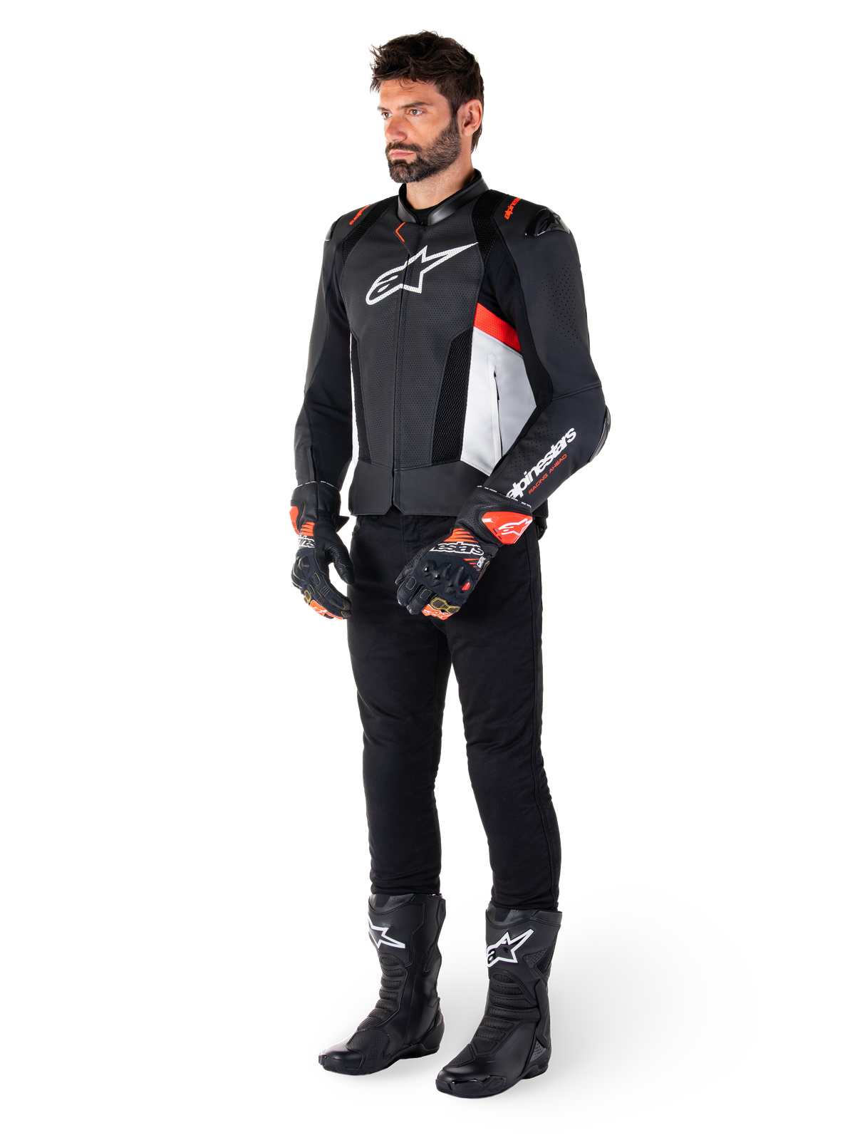 Chaqueta de cuero Alpinestars Missile V3 Airflow, Negro Blanco Rojo Fluo, usada por un modelo masculino con pantalones negros, guantes de carreras negros y botas negras, con cuero perforado para ventilación, logotipo blanco en el pecho y detalles en rojo fluo, diseñada para un rendimiento premium en competición y conducción deportiva.