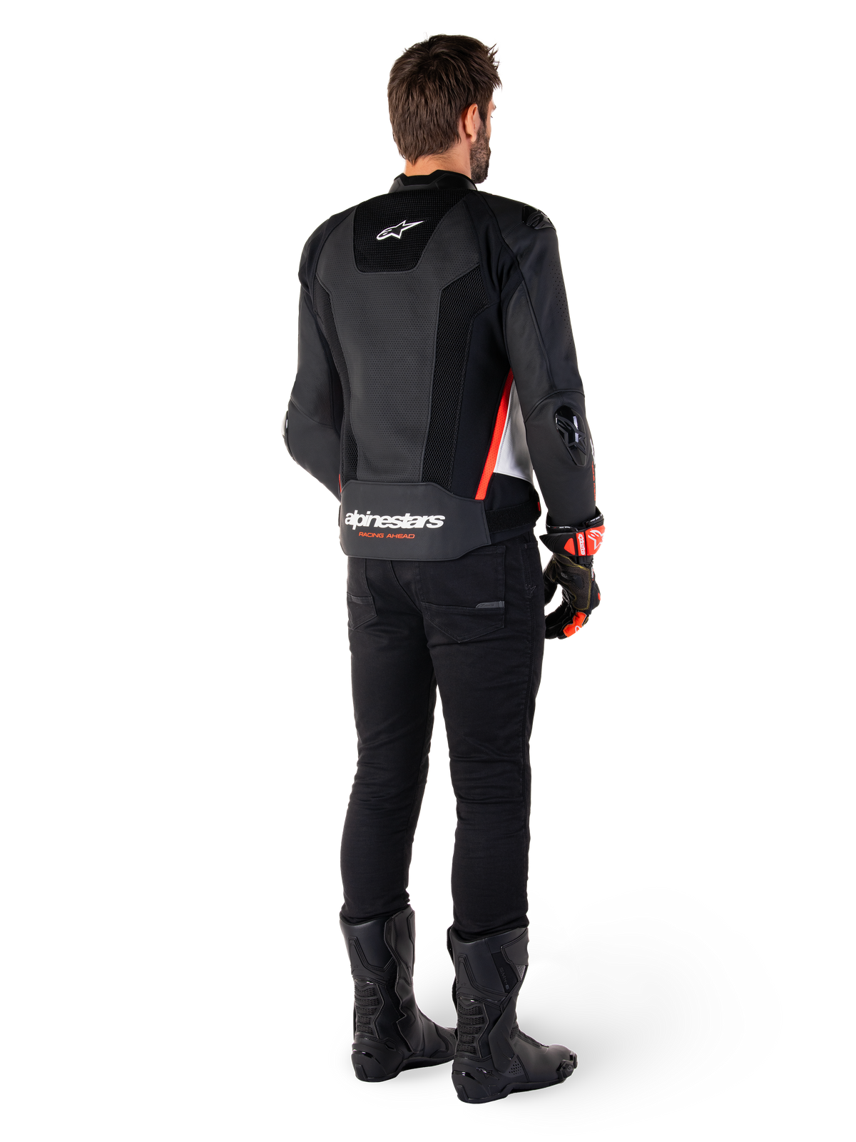 Piloto visto desde la parte posterior vistiendo la chaqueta de cuero Alpinestars Missile V3 Airflow en color negro, blanco y rojo flúor, combinada con pantalones y botas negras, con extensas perforaciones en el cuero para ventilación, protecciones DFS en los hombros y el logotipo de Alpinestars destacado en la parte inferior de la espalda.