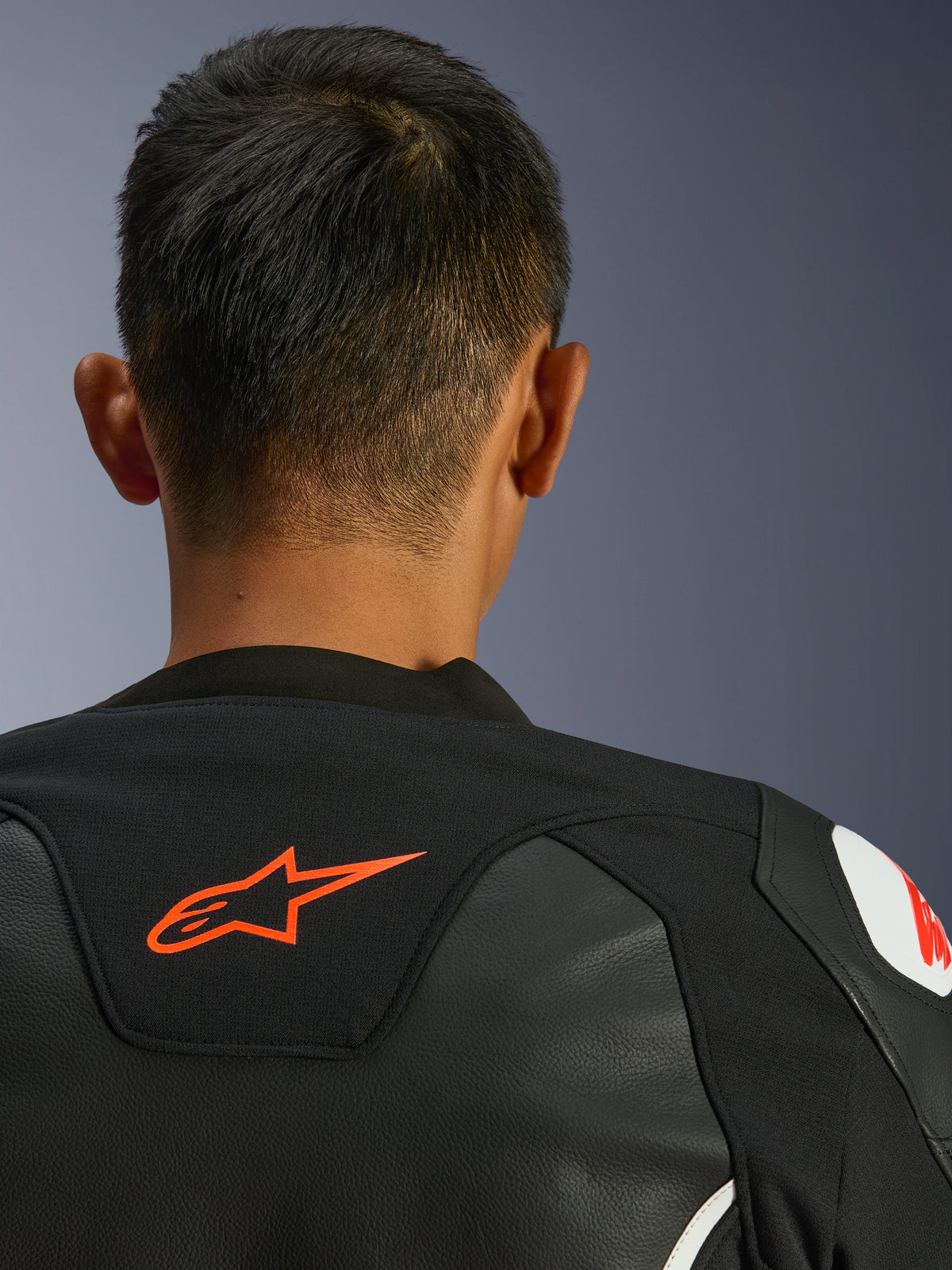 Chaqueta de cuero Alpinestars GP Force V2, negro y blanco, vista de cerca desde atrás del cuello y los hombros, logotipo de Alpinestars en rojo, cuero de primera calidad con paneles elásticos de tejido, diseño de rendimiento deportivo
