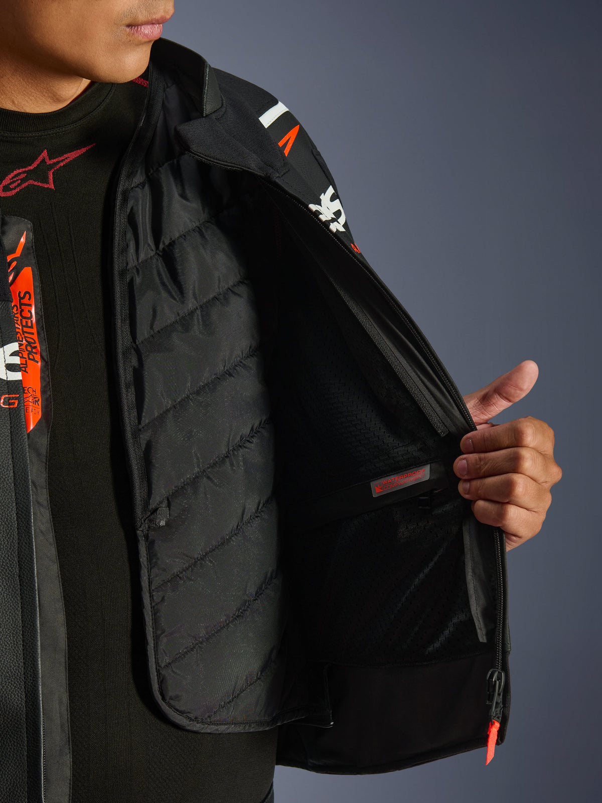 Chaqueta de cuero Alpinestars GP Force V2, negro y blanco, vista detallada del interior que muestra el forro térmico acolchado desmontable y el bolsillo interior impermeable, sobre una capa base negra, equipamiento de alto rendimiento para motociclismo