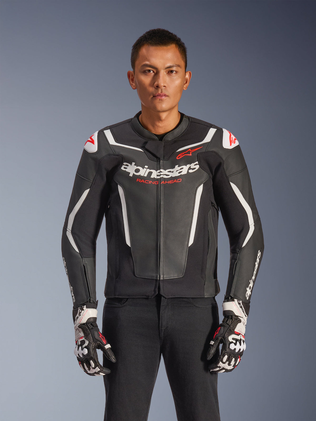 Alpinestars GP Force V2 Leather Jacket, chaqueta de moto de cuero negra y blanca con detalles rojos, construcción de cuero premium con armadura protectora, marca Racing Ahead, usada con guantes a juego