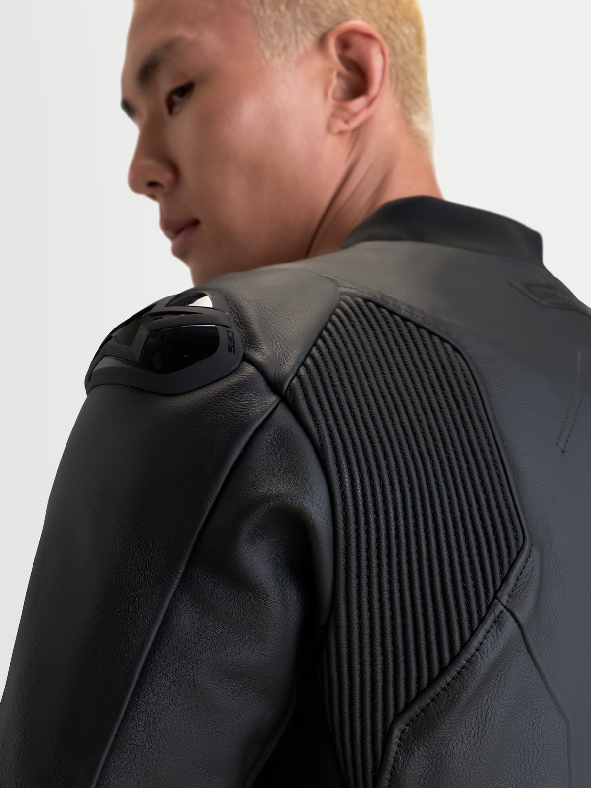 Alpinestars Caliber V 2 chaqueta de cuero, chaqueta de moto negra, vista de cerca enfocada en la protección de hombro y paneles de movilidad de acordeón en un piloto