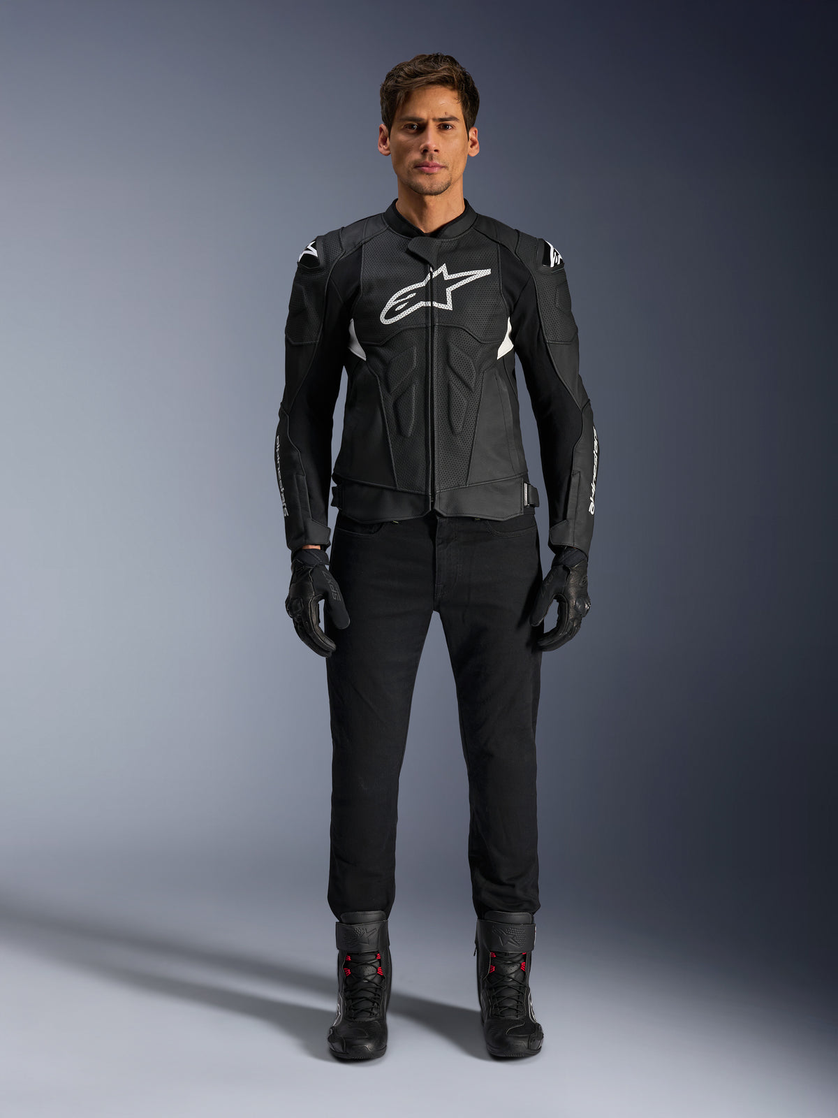 Alpinestars Dusk Airflow Leather Jacket, Black and White, motorcycle leather jacket with perforated panels for airflow, white Astars logo on chest, worn by a male rider with black pants, gloves, and riding boots, professional studio shot for sport motorcycle gear.
