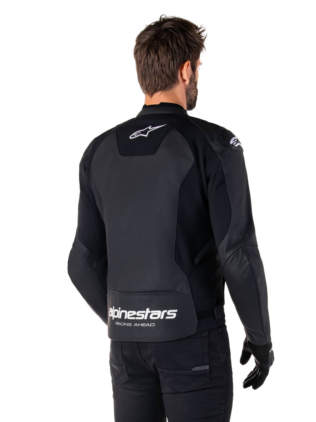 Chaqueta de cuero Alpinestars Faster V3, negra y blanca, vista trasera en un piloto, con el logotipo de la estrella blanca en la parte superior de la espalda y gran marca Alpinestars con "Racing Ahead" en la parte inferior, parte trasera alargada para mayor cobertura y construcción de cuero deportivo premium