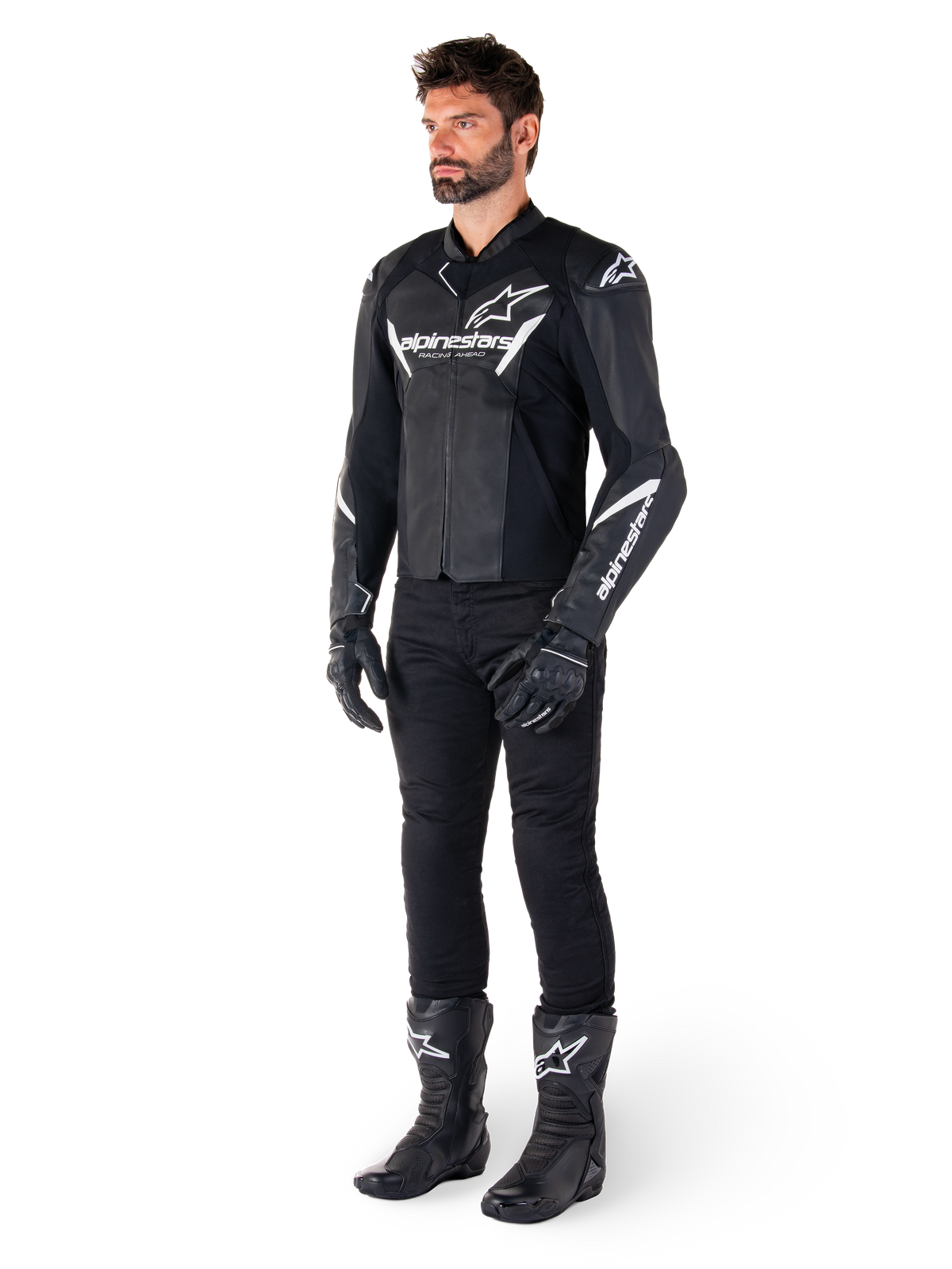 Modelo masculino vistiendo la chaqueta de cuero Alpinestars Faster V3, chaqueta de conducción deportiva, negro y blanco, combinada con pantalones de motociclismo, guantes y botas negros, con logotipos y marca en blanco, silueta de ajuste deportivo para carreras en carretera