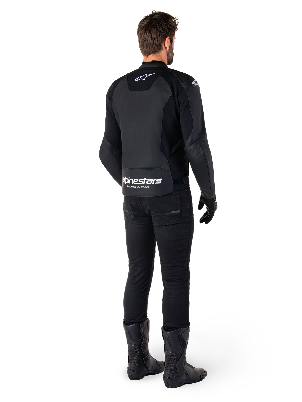 Chaqueta de cuero Alpinestars Faster V3, vista trasera, negro y blanco, con la marca 'alpinestars RACING AHEAD' en la parte inferior de la espalda, combinada con pantalones de conducción y botas negras, chaqueta de cuero para moto de inspiración deportiva con paneles elásticos.