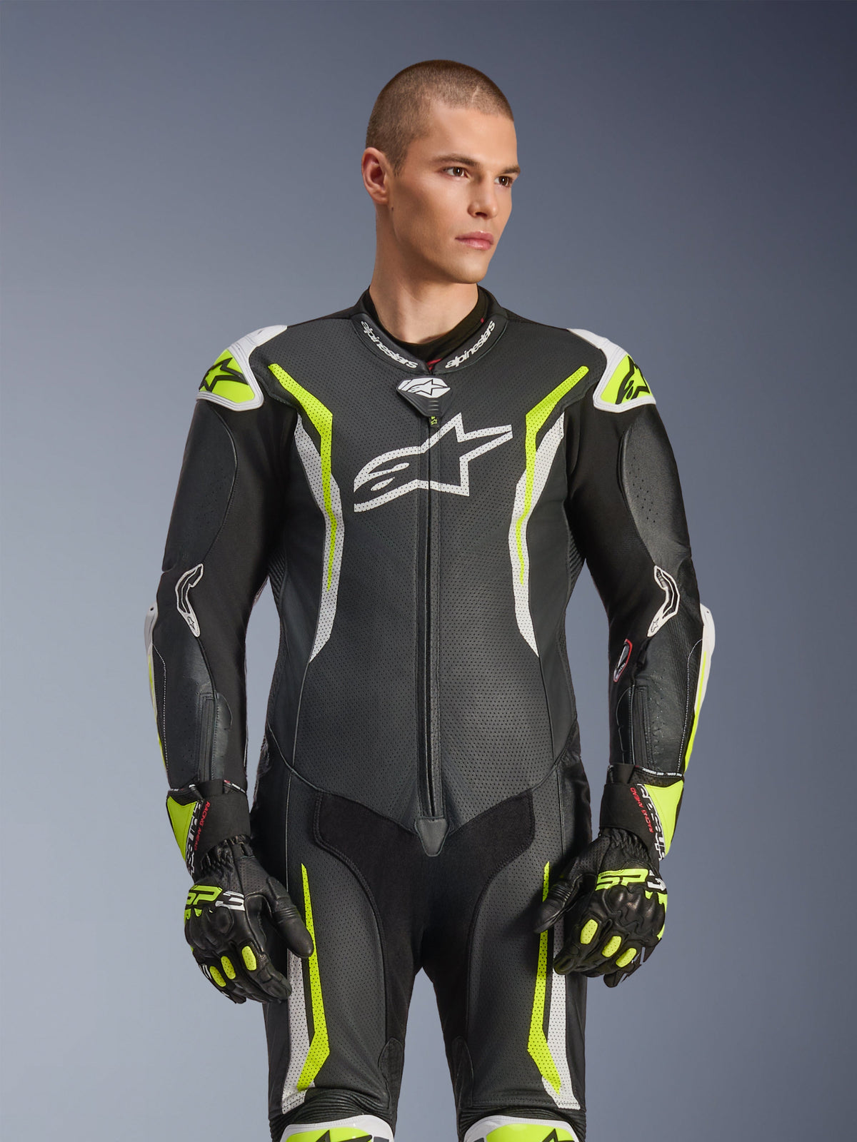 Mono de cuero de una pieza Alpinestars GP Tech V5, negro, blanco y amarillo flúor, equipamiento de carreras profesional, cuero perforado con un gran logotipo Astar blanco en el pecho, detalles en amarillo flúor y blanco, usado con guantes de carreras a juego