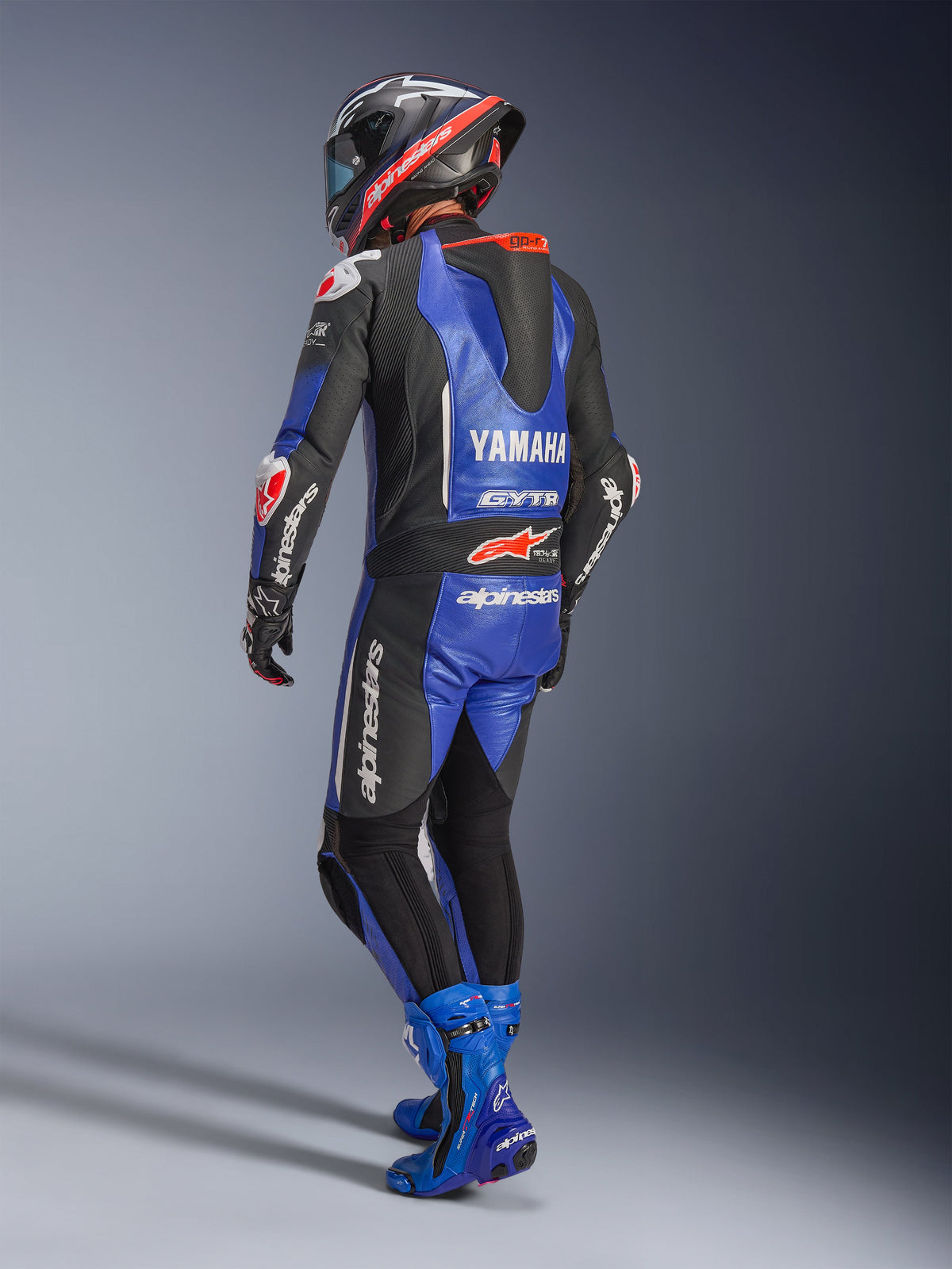 Alpinestars Yamaha GP-R7 Mono de cuero de una pieza, azul metálico, negro y blanco, vista trasera que muestra la joroba aerodinámica de competición y el logotipo de Yamaha, usado con botas de competición y casco azules a juego, mono de cuero profesional de alto rendimiento para carreras en pista