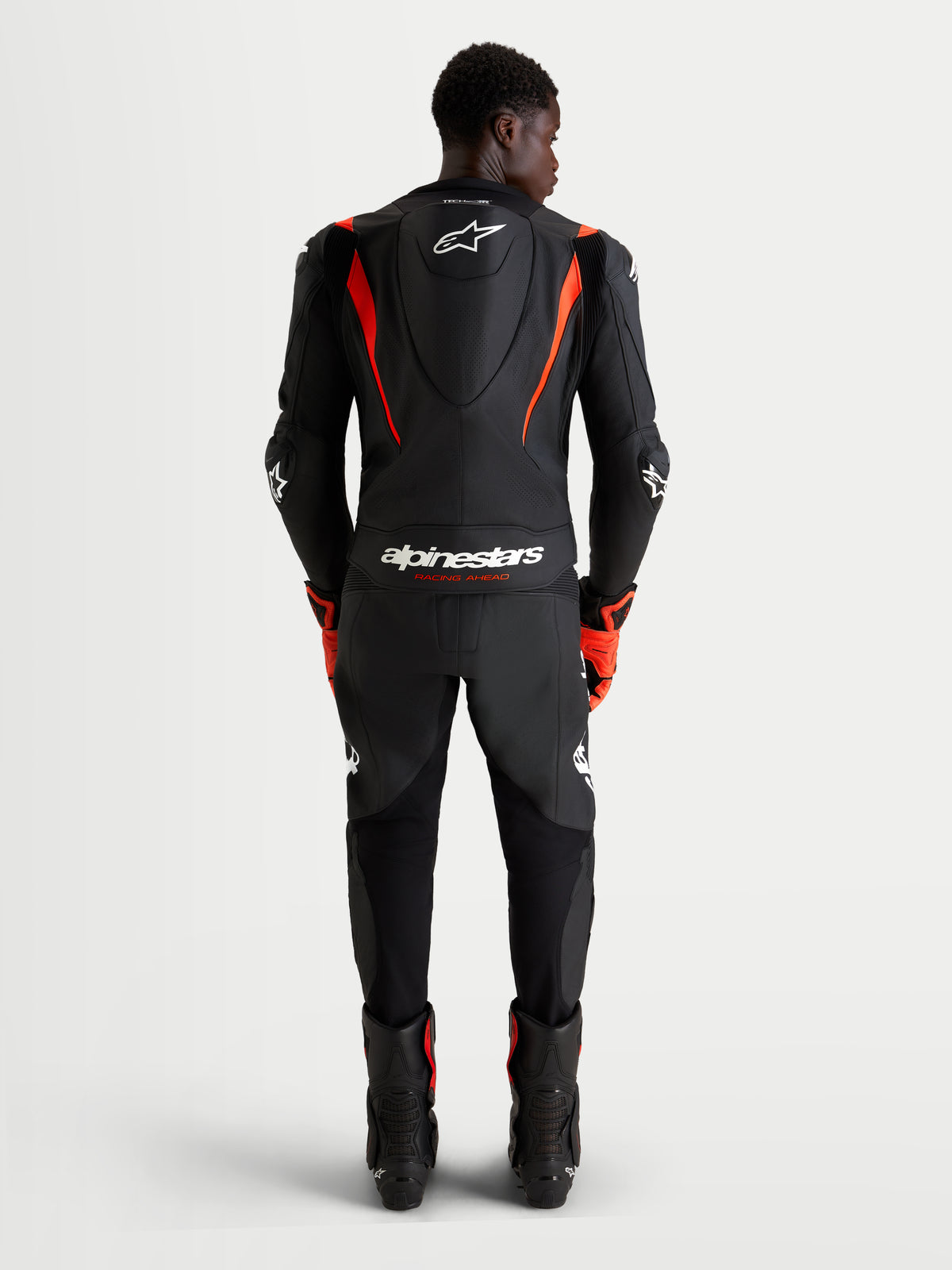 Alpinestars Missile V3 mono de cuero de 2 piezas, mono de moto para carreras, negro y rojo flúor, con joroba aerodinámica y protección con certificación AAA, vista trasera de piloto con equipamiento