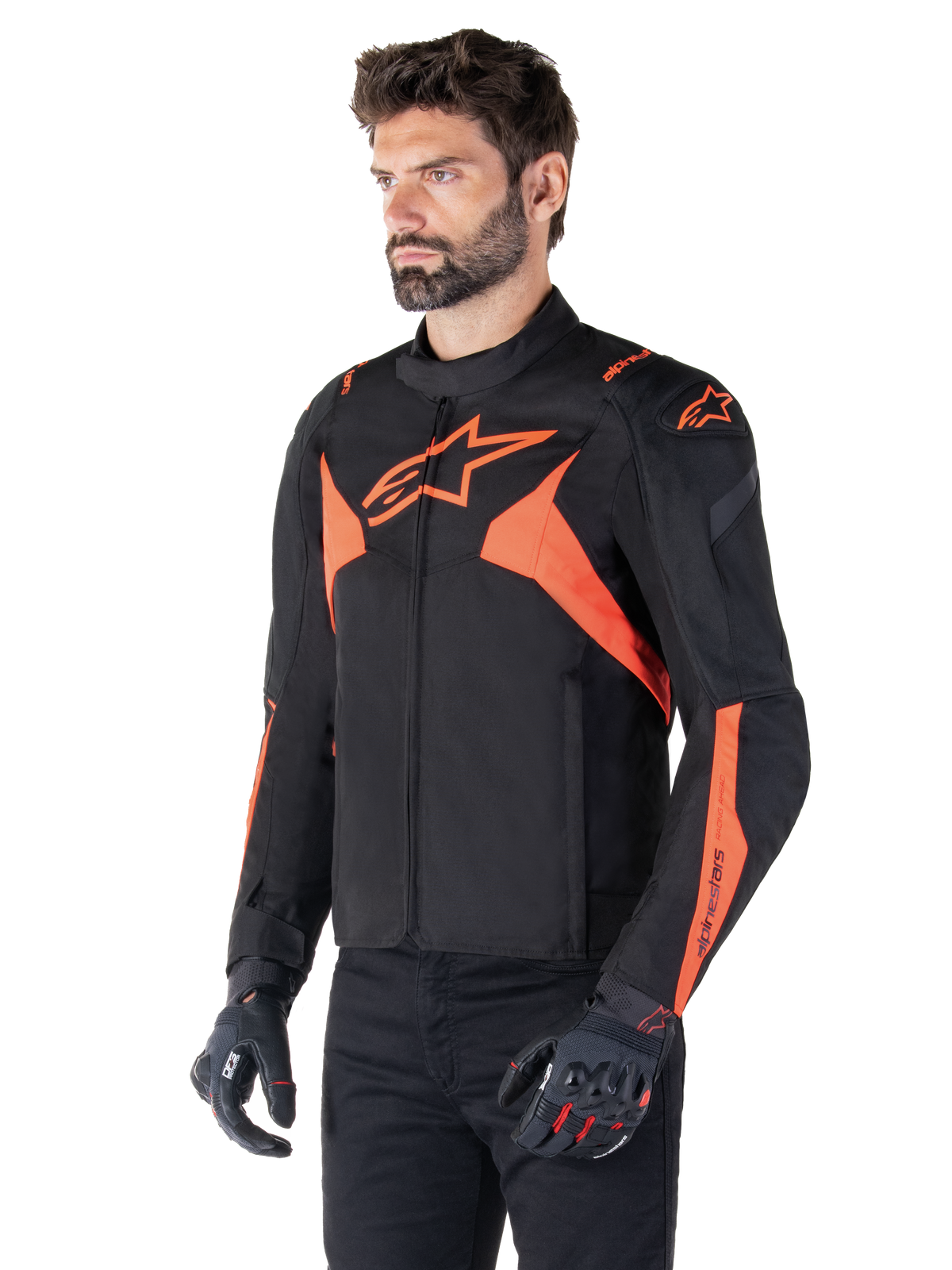 Alpinestars T-Jaws V4 Waterproof Jacket, Black and Red Fluo, sport motorcycle jacket worn by a male model, featuring prominent orange star logos on the chest and shoulders, paired with black gloves and pants