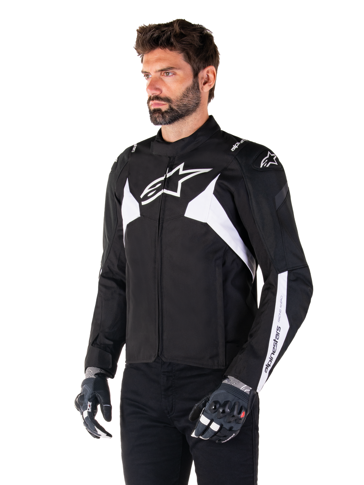 Chaqueta impermeable Alpinestars T-Jaws V4, en negro y blanco, lucida por un modelo con guantes de moto, con destacados logos y detalles de Alpinestars en blanco, chaqueta de moto textil con ajuste deportivo para carretera