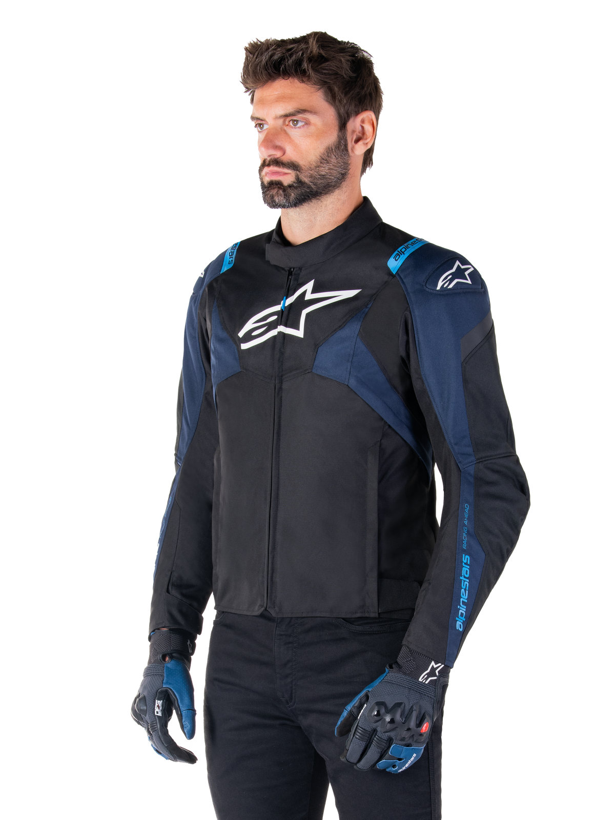 Chaqueta impermeable Alpinestars T-Jaws V4, chaqueta de moto, negro, azul oscuro y azul Blithe, llevada por un modelo con guantes a juego y pantalones negros, con logotipos blancos de Alpinestars en el pecho y los hombros y detalles azules en las mangas, equipación deportiva de tejido para moto