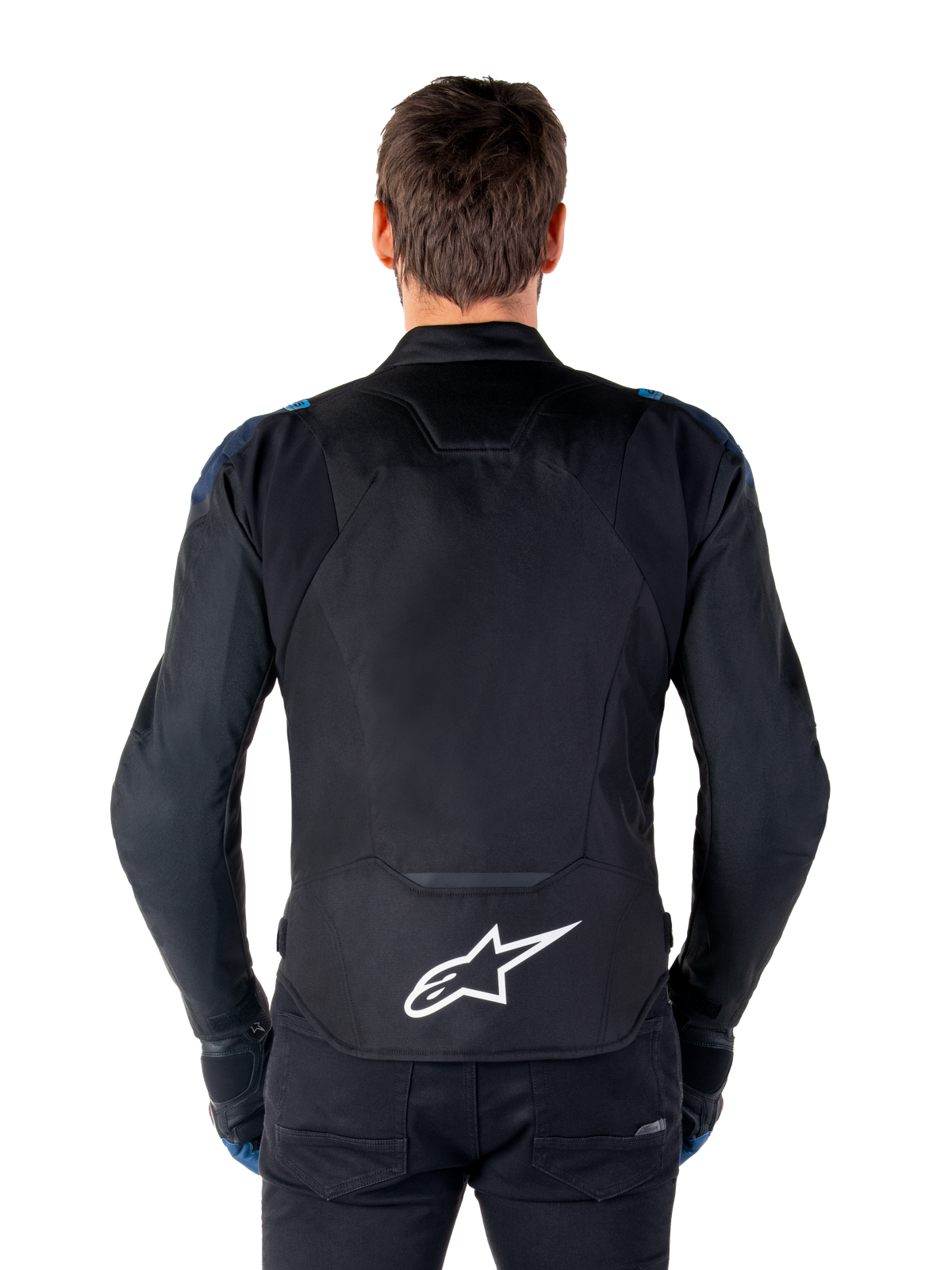 Alpinestars T-Jaws V4 Waterproof Jacket, chaqueta de moto, negro, azul oscuro y azul blithe, vista posterior en un modelo, con un gran logotipo blanco de Alpinestars en la parte inferior de la espalda, detalles en azul oscuro en los hombros y una silueta deportiva estilizada.