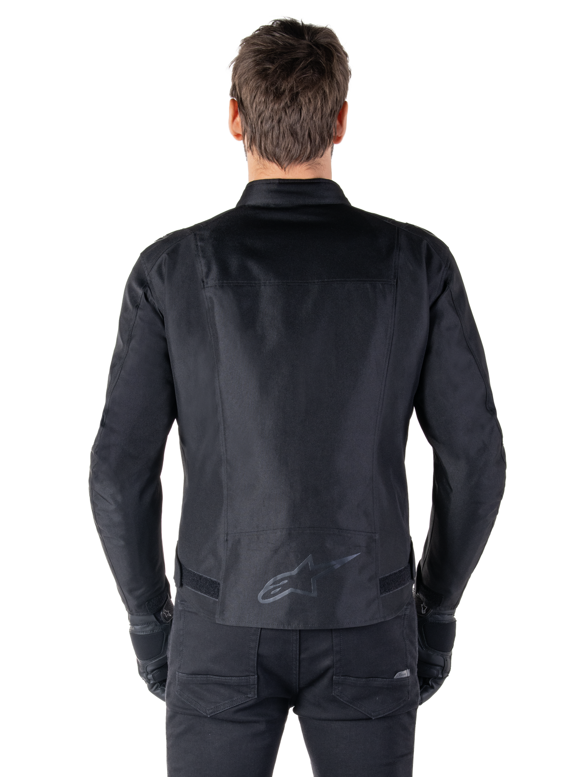 Chaqueta impermeable Alpinestars T-SPS V2, negro, vista trasera que muestra la silueta de corte deportivo, logo reflectante de Alpinestars en la parte inferior de la espalda y espalda extendida para mayor cobertura al conducir.