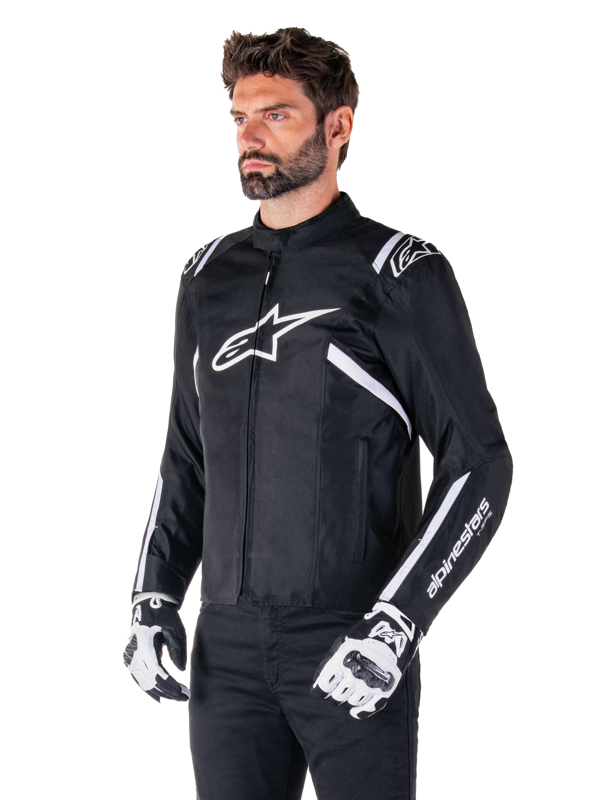 Alpinestars T-SPS V2 Waterproof Jacket, Black and White, worn by male model with matching motorcycle gloves, sport-cut textile jacket with white Alpinestars logos on chest and shoulders, 'alpinestars T-SPS' branding on sleeve, sleek race-inspired motorcycle gear