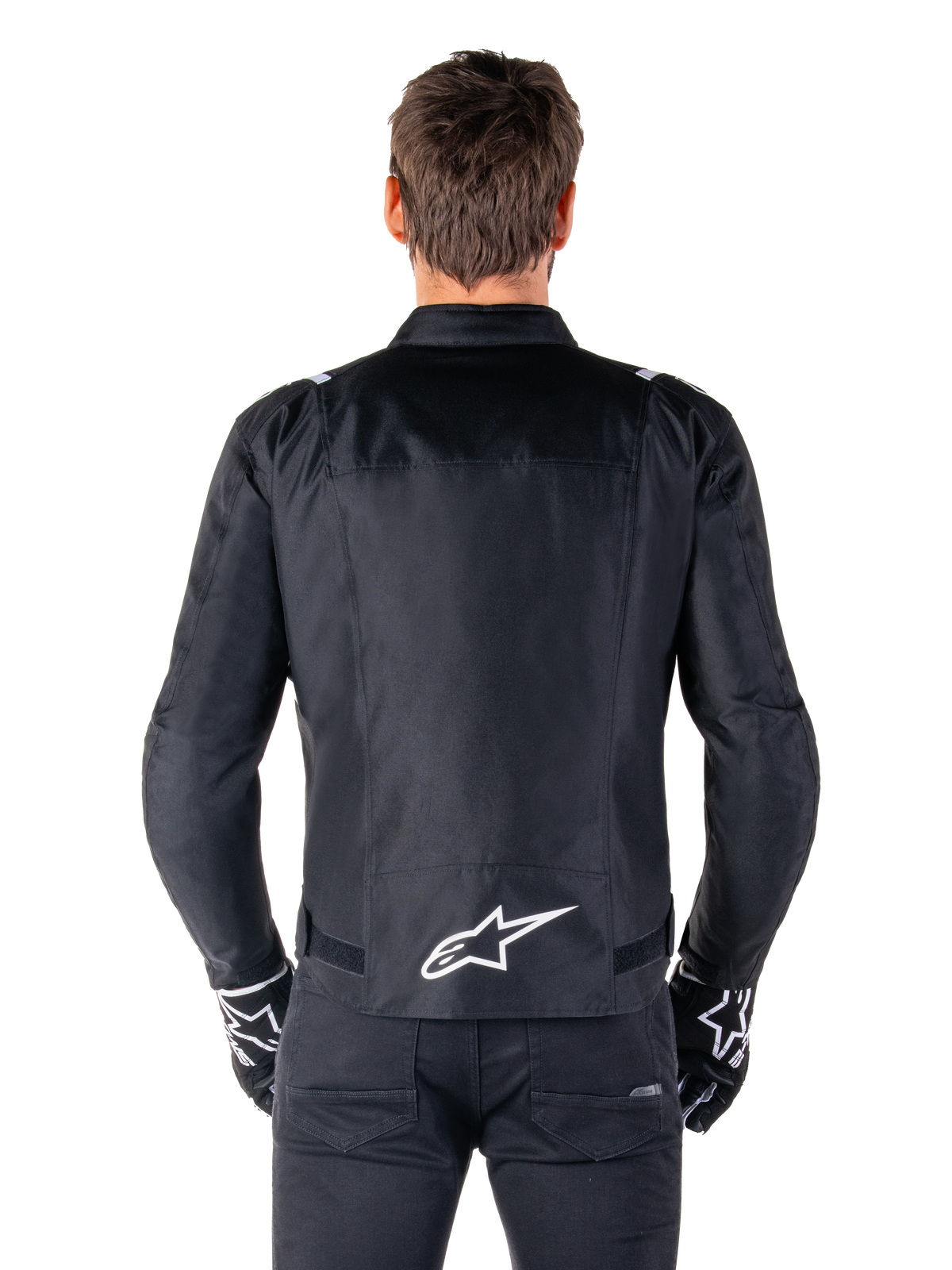 Alpinestars T-SPS V2 Waterproof Jacket, Black and White, back view showing white Alpinestars logo on lower back, worn with black pants and gloves, sport cut textile motorcycle jacket