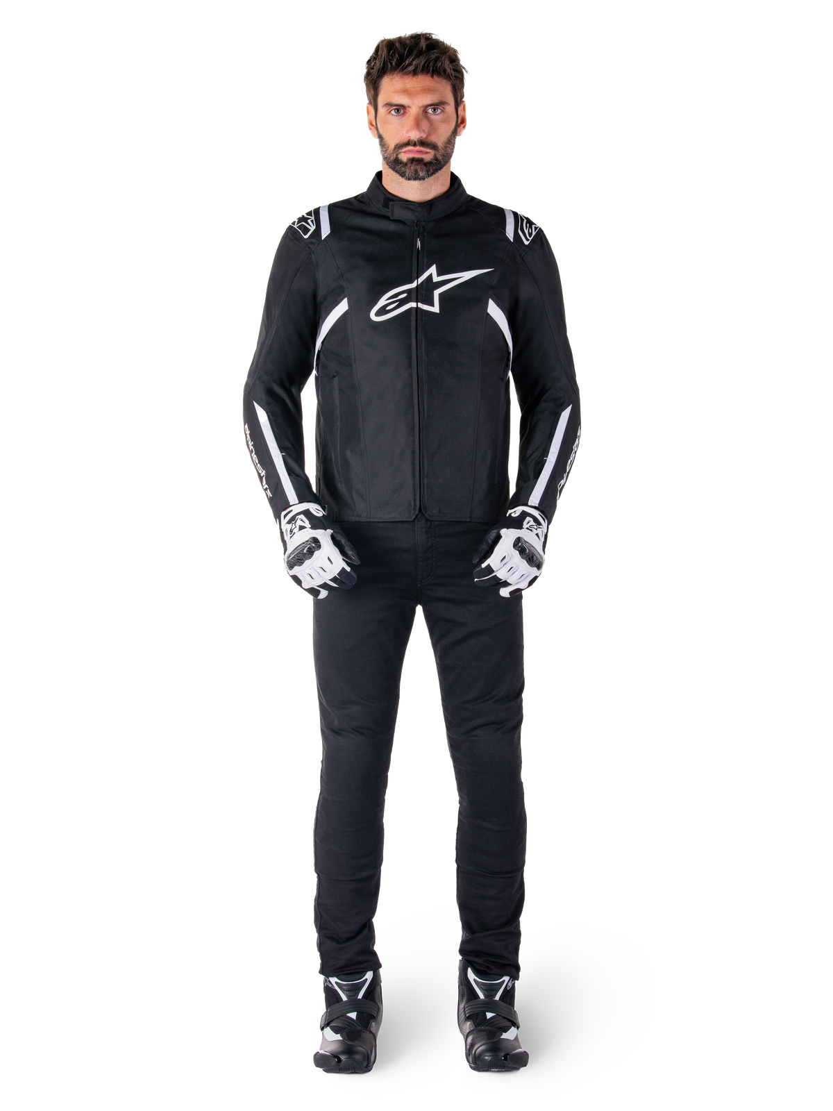 Alpinestars T-SPS V2 Waterproof Jacket, Black and White, worn by male model with black pants and matching gloves, featuring white Alpinestars logo on chest and accents on sleeves, sport-cut silhouette for all-weather motorcycle riding
