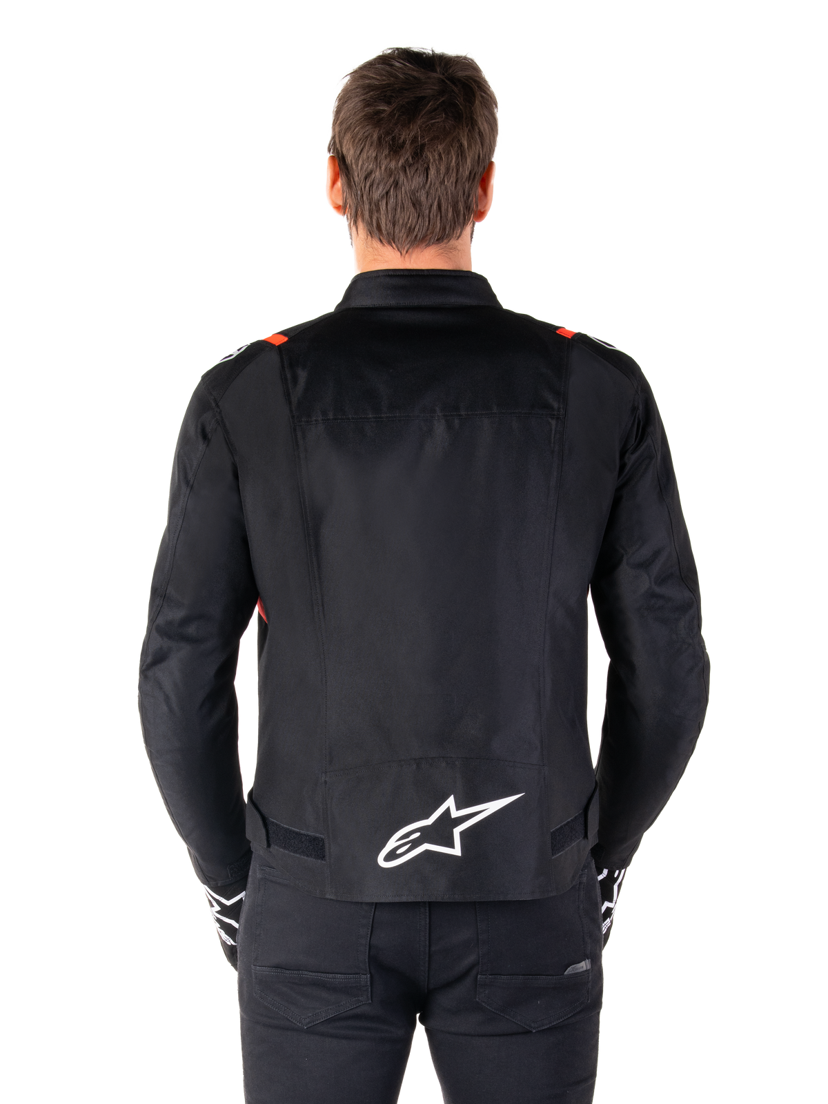 Alpinestars T-SPS V2 Waterproof Jacket, Black with White and Red Fluo accents, rear view featuring a large white Alpinestars logo on the lower back, sport cut textile motorcycle jacket, worn with black pants and gloves