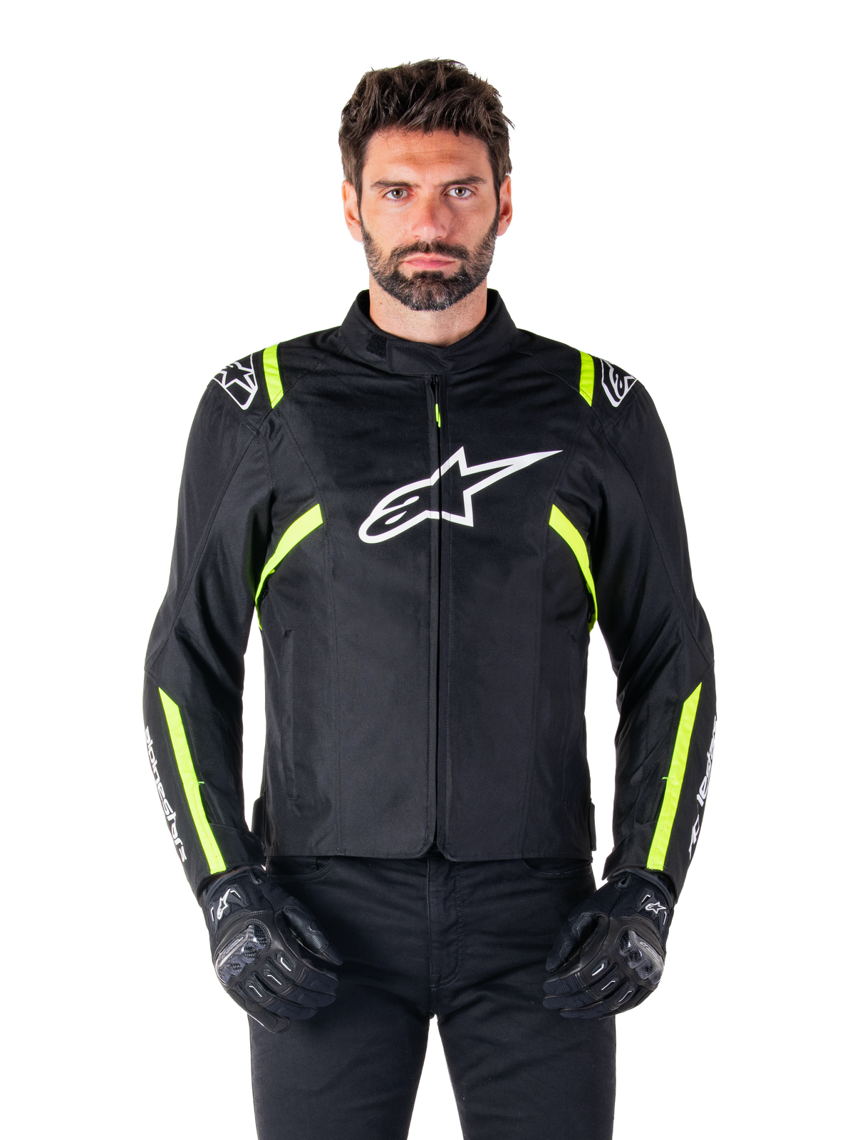 Alpinestars T-SPS V2 Waterproof Jacket, chaqueta de moto, negra con detalles en blanco y amarillo flúor, usada por un modelo con guantes negros, con el logo de la estrella blanca en el pecho y franjas amarillo neón en las mangas y hombros, equipamiento textil deportivo para cualquier clima