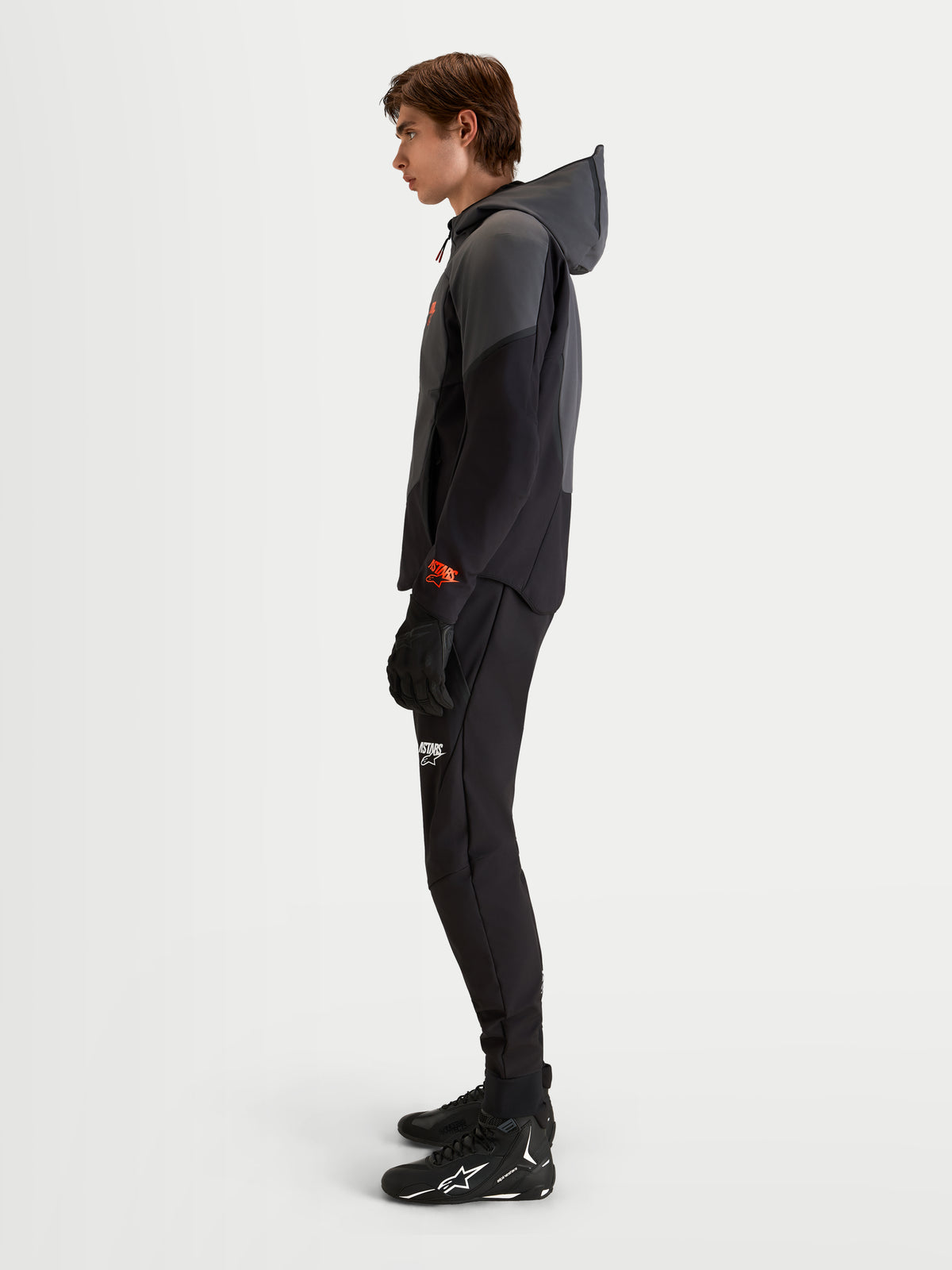 Alpinestars Aeroshell Waterproof Jacket, chaqueta de moto softshell con capucha para hombre en negro y gris oscuro, con certificación CE, vestida por un modelo en vista de perfil