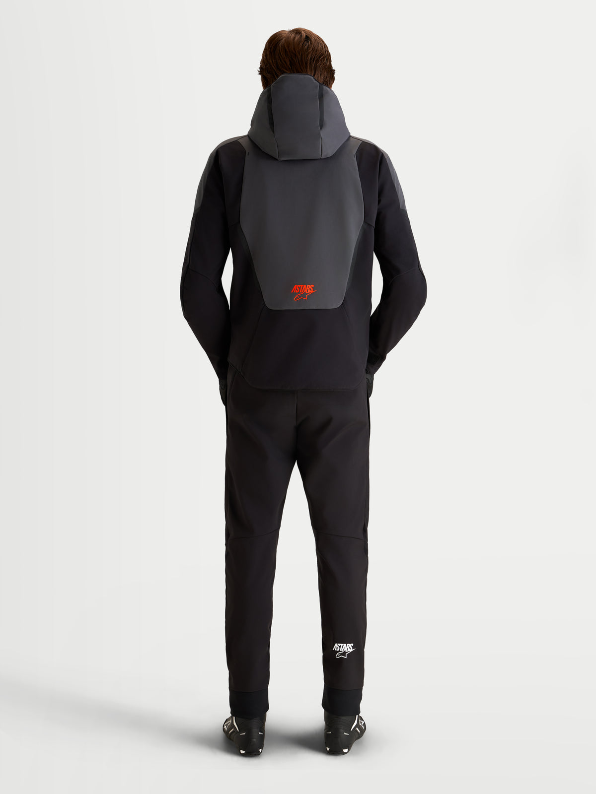Alpinestars Aeroshell WP Chaqueta de moto, impermeable, negro y gris oscuro, vista trasera con capucha integrada y logo rojo, equipo de protección textil certificado CE