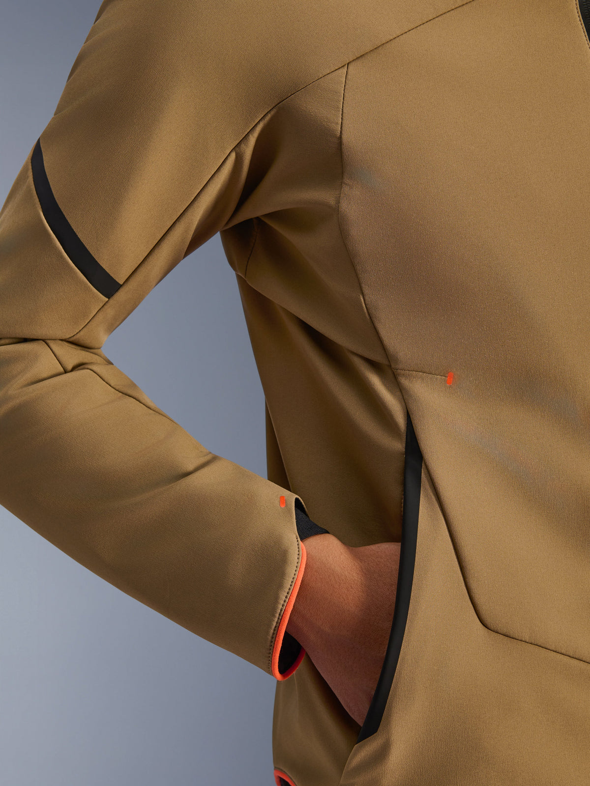 Primer plano de la chaqueta impermeable Alpinestars Aeroshell, caqui oscuro con detalles en negro y naranja flúor, detalle del bolsillo oculto con cremallera y el puño de la manga, tejido softshell elástico para motociclismo