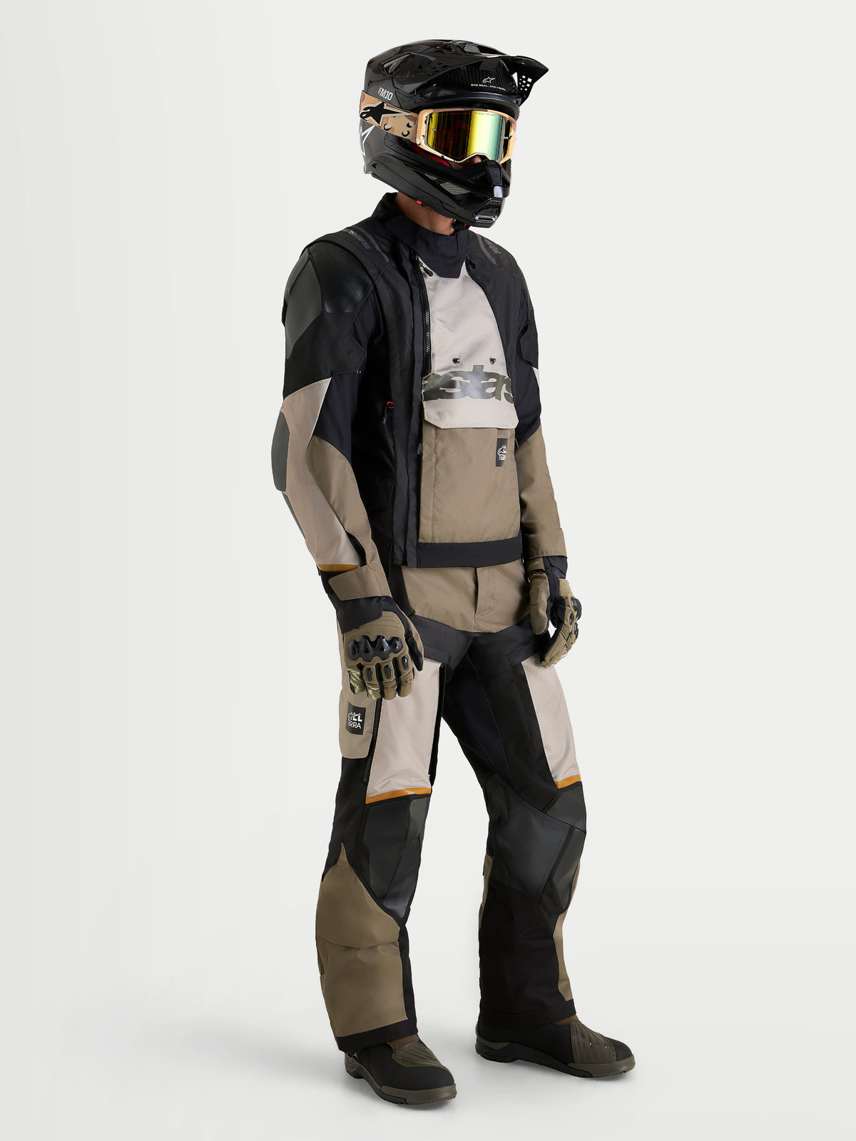 Alpinestars Harok V2 Drystar, chaqueta de moto todoterreno para hombre de color aluminio, marrón y negro, vestida por un piloto con casco y pantalones a juego
