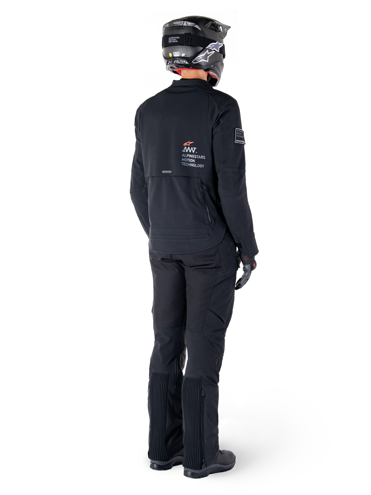 Chaqueta Alpinestars AMT-8 Stretch Drystar® XF, negro, vista trasera de un piloto que lleva la chaqueta con pantalones negros a juego y casco negro, con la marca 'Alpinestars Motion Technology' en la espalda, material elástico técnico para conducción de aventura