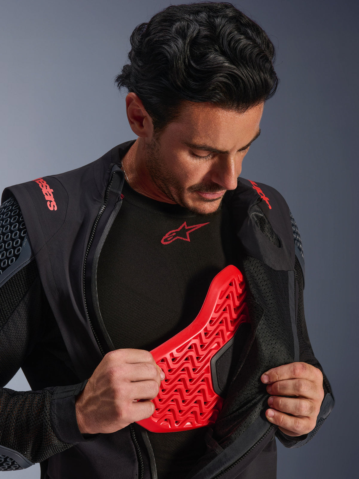 Chaqueta laminada Alpinestars Halo Pro Drystar® XF en Black Dark Shadow, vestida por un modelo y abierta para revelar un protector de pecho Nucleon Flex Pro rojo, chaqueta técnica de moto con armadura integrada, equipamiento para conducción de aventura.