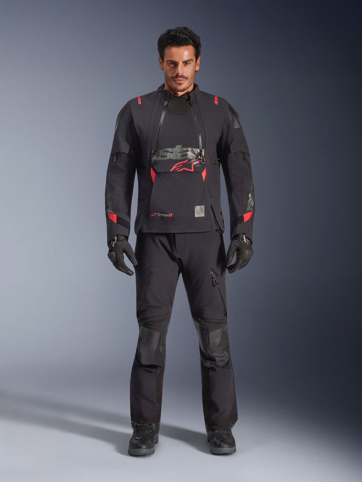 Chaqueta laminada Alpinestars Halo Pro Drystar® XF, negro Dark Shadow con detalles en rojo, conjunto de equipamiento de moto de aventura que incluye pantalones y guantes a juego, diseño textil modular con paneles de ventilación frontales y logo prominente en el pecho.