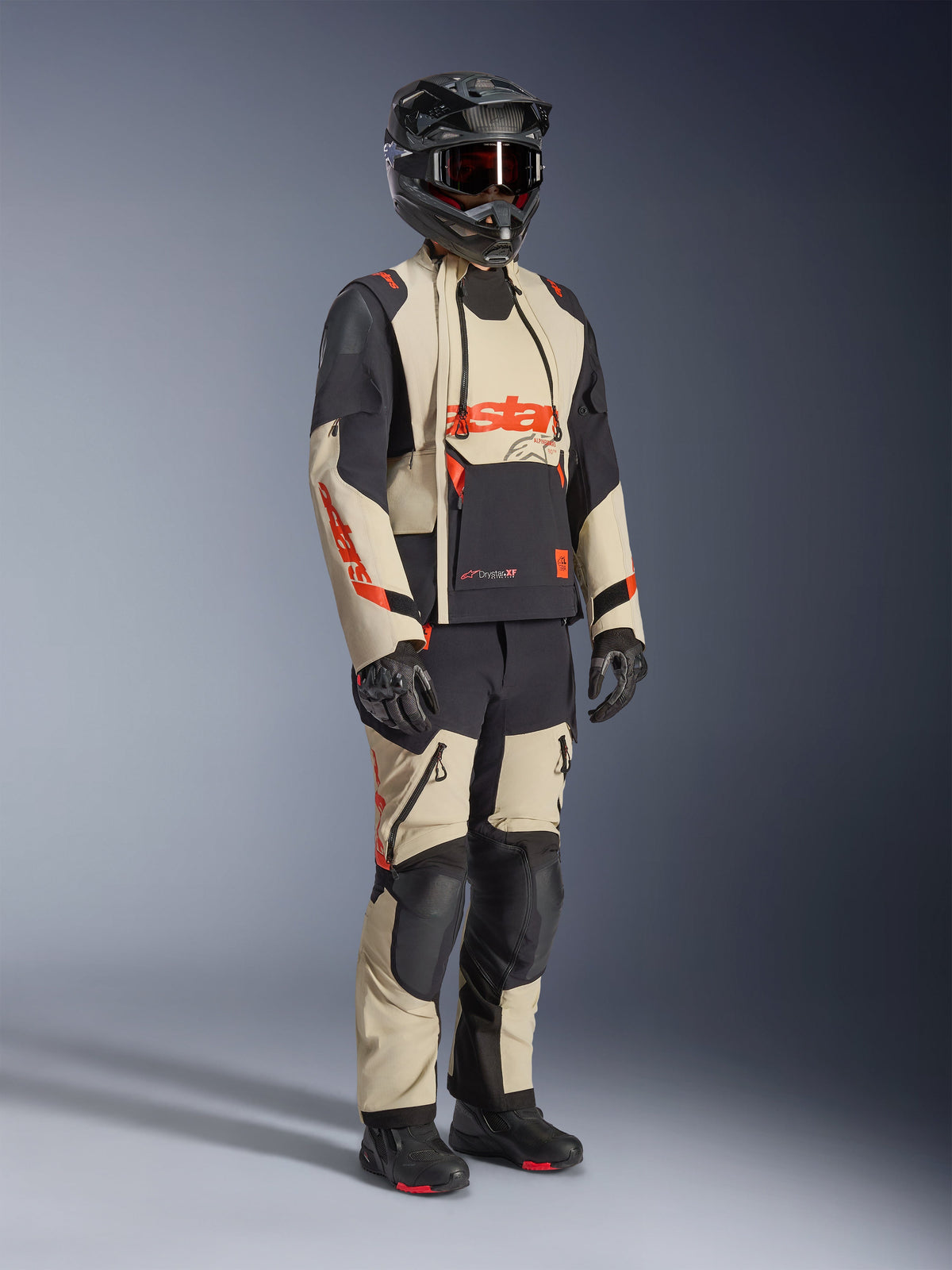 Alpinestars Halo Pro Drystar® XF Laminated Jacket in Mastic Black, adventure motorcycle jacket worn with matching pants, full-face helmet, gloves, and boots, featuring tan and black panels with red logos, technical multi-season design.