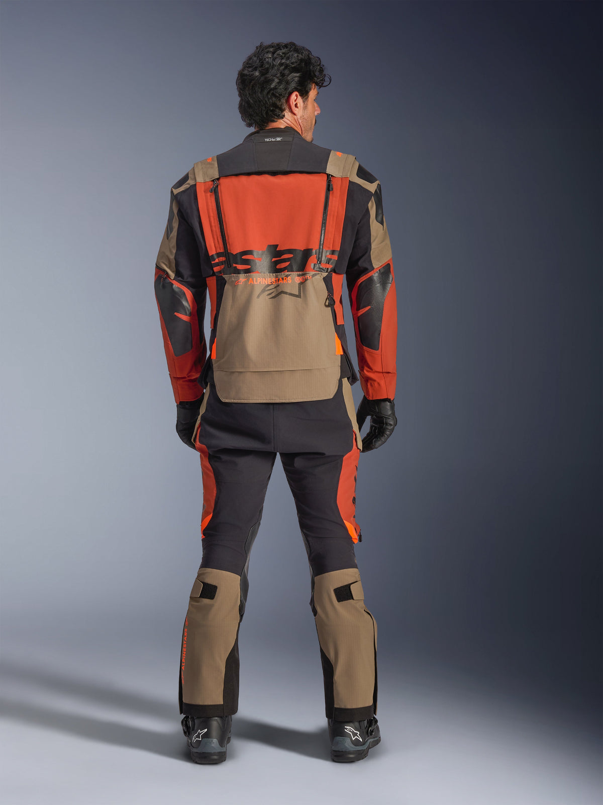 Chaqueta laminada Alpinestars Halo Pro Drystar® XF, Walnut Rust Black, vista trasera, chaqueta de aventura con diseño modular y gran bolsillo trasero impermeable, combinada con pantalones técnicos a juego.
