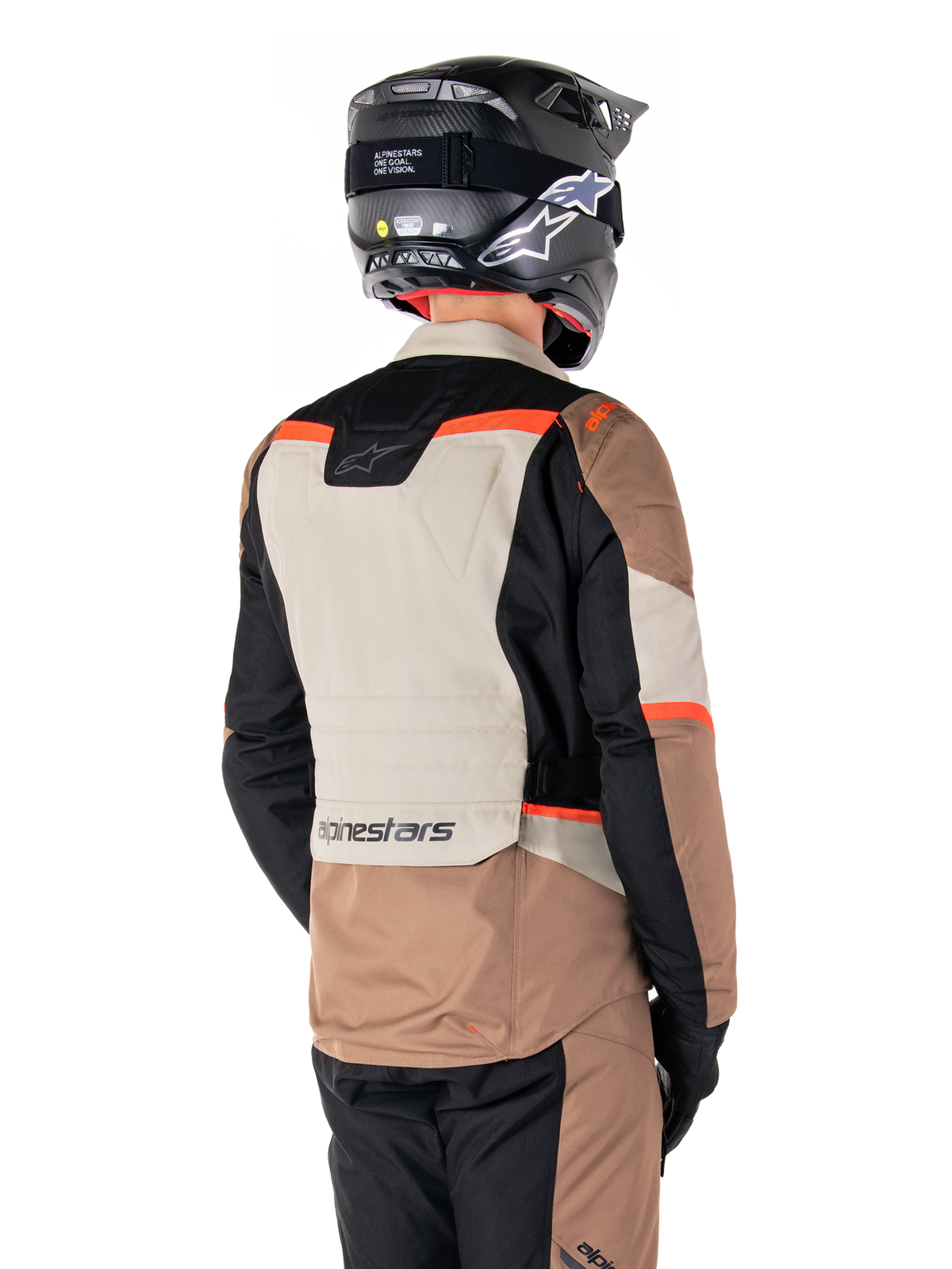 Chaqueta Alpinestars ST-1 Waterproof, chaqueta de touring de aventura, caqui oscuro, arena, negro y rojo flúor, vista trasera que muestra paneles textiles con bloques de color, detalles en rojo fluorescente y el logotipo de Alpinestars en la parte inferior de la espalda, usada por un piloto con un casco negro.