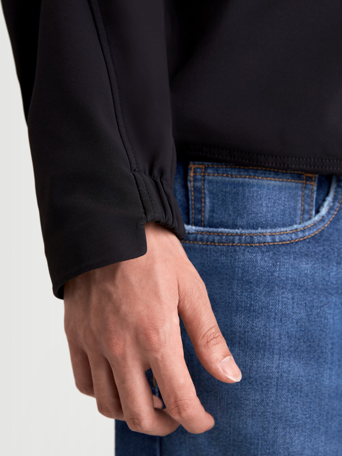 Alpinestars C 5 Drystar Chaqueta, chaqueta de moto urbana para hombre, negra, vista en primer plano del detalle del puño elástico llevado por un modelo con vaqueros azules
