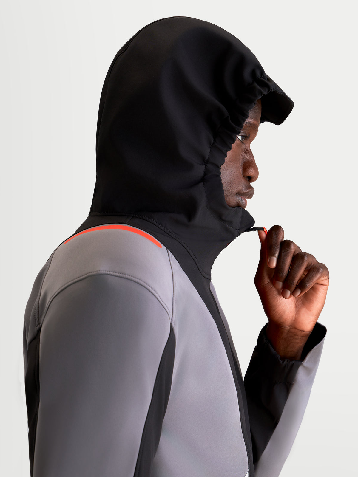 Alpinestars C-5 Drystar chaqueta de moto urbana contemporánea para hombre, en negro y gris oscuro, vista de perfil lateral de un modelo con la chaqueta impermeable puesta, la capucha integrada levantada y ajustando la cremallera frontal