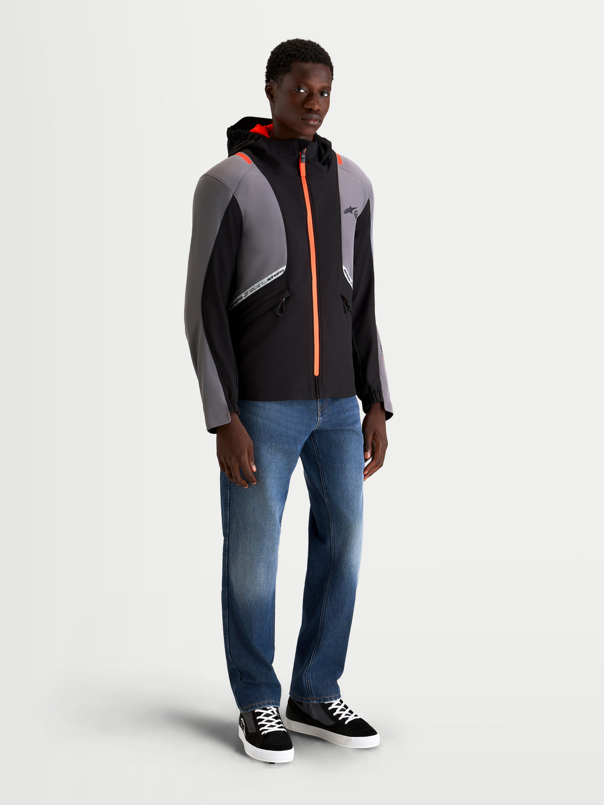 Alpinestars C-5 Drystar Chaqueta, chaqueta de moto urbana contemporánea para hombre en negro y gris oscuro, con capucha integrada y detalles de cremallera en naranja brillante, vista frontal en modelo