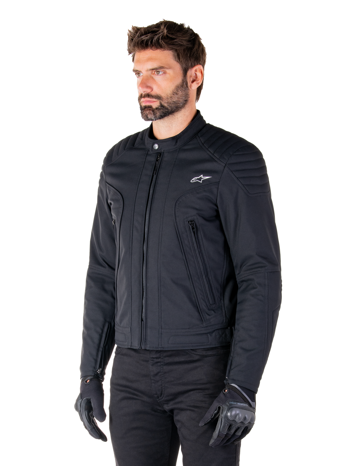 Chaqueta Alpinestars Clayton WR, negra, chaqueta de moto urbana de textil con detalles acolchados en hombros y antebrazos, diseño ajustado, acabado mate, usada por un piloto con guantes negros.