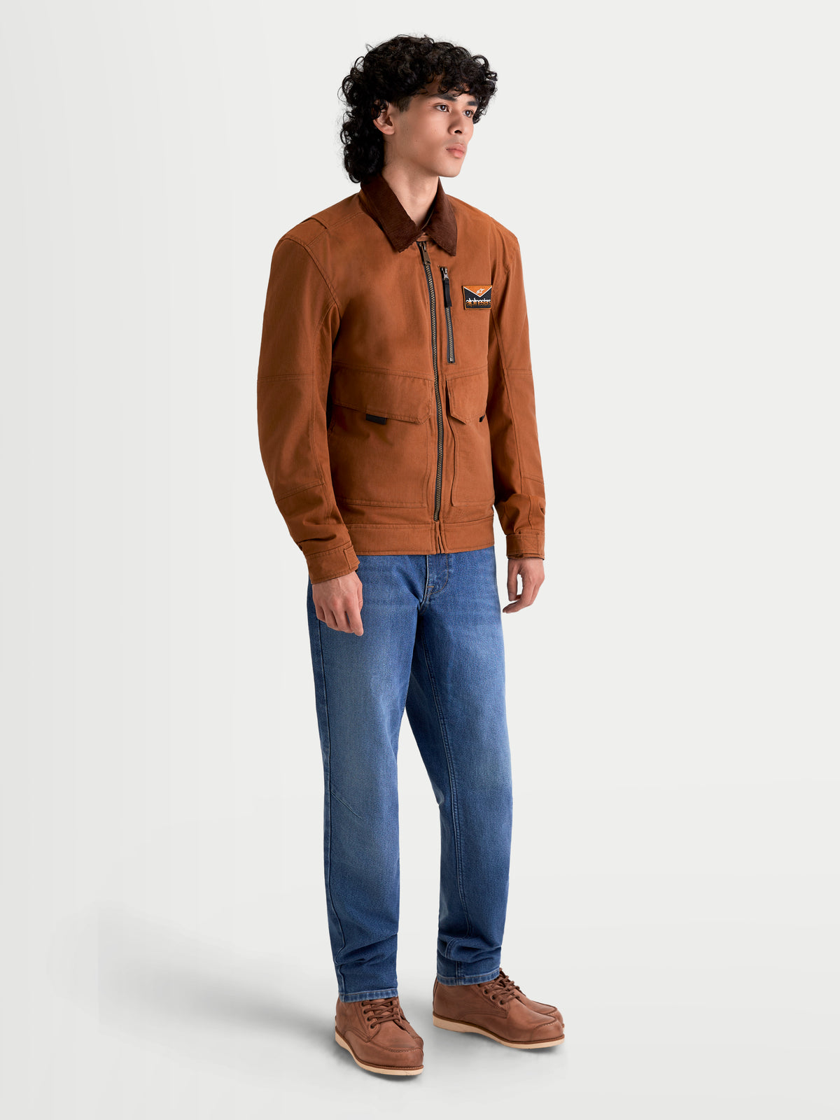 Alpinestars Mustang Waterproof Jacket, men's urban motorcycle jacket in dark rust and dark brown, side profile view on a model wearing workwear-styled textile gear and blue jeans.