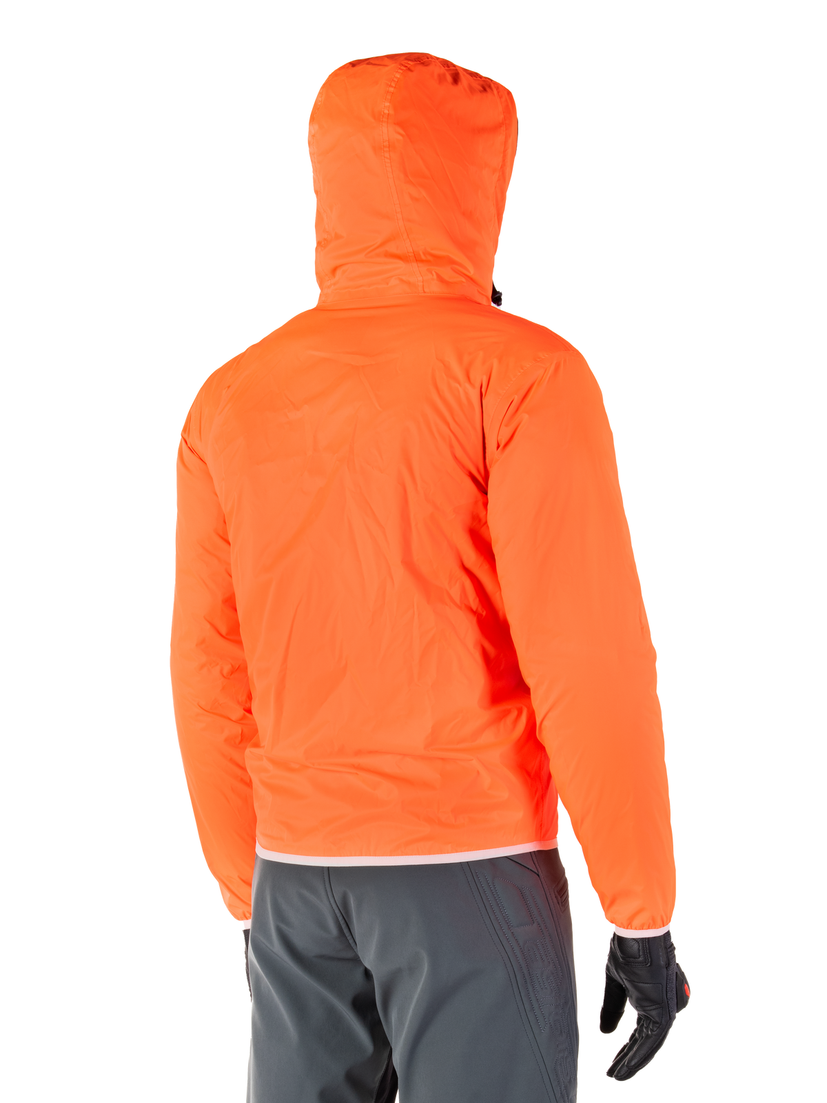 Chaqueta impermeable Alpinestars Mohobbs, forro impermeable de emergencia plegable en naranja flúor brillante, vista trasera que muestra la capucha para tormentas, combinada con pantalones de conducción gris oscuro y guantes negros, equipamiento urbano de motociclismo ligero e impermeable