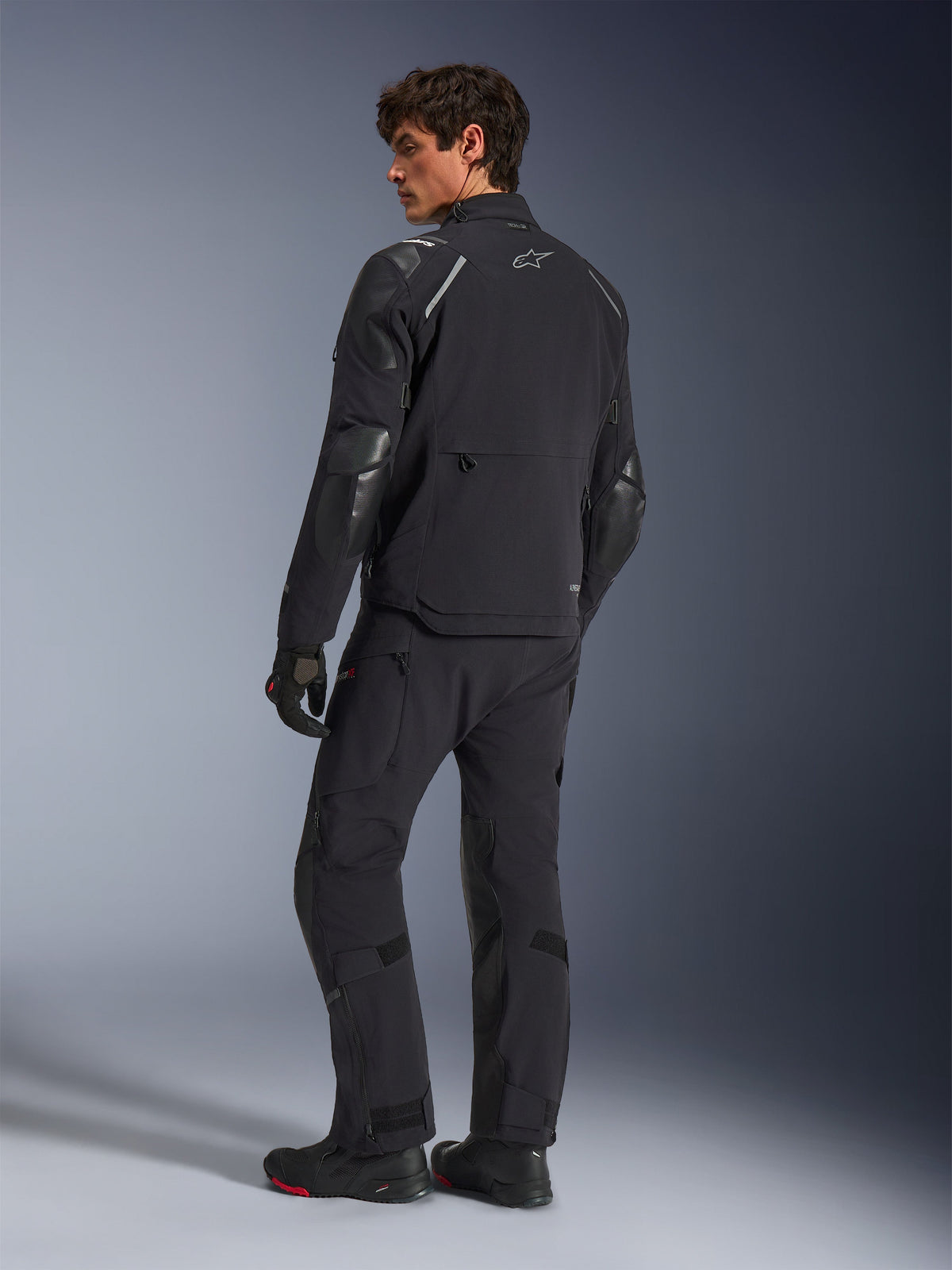 Alpinestars Andes Pro Drystar® XF Jacket, Adventure Motorcycle Jacket, Black, back view worn with matching pants and boots, featuring reinforced panels and silver star logo, technical all-weather riding gear
