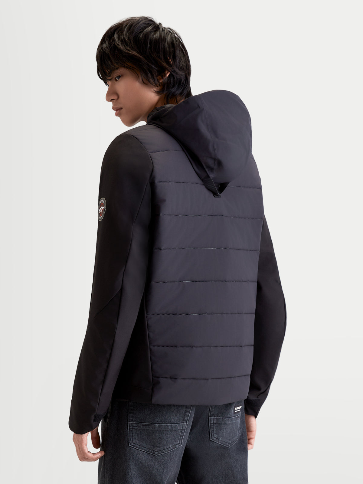 Alpinestars Therma-Tech Waterproof Jacket, men's urban motorcycle jacket in black, rear three-quarter view showing sonic-welded down construction and integrated hood system worn by a model