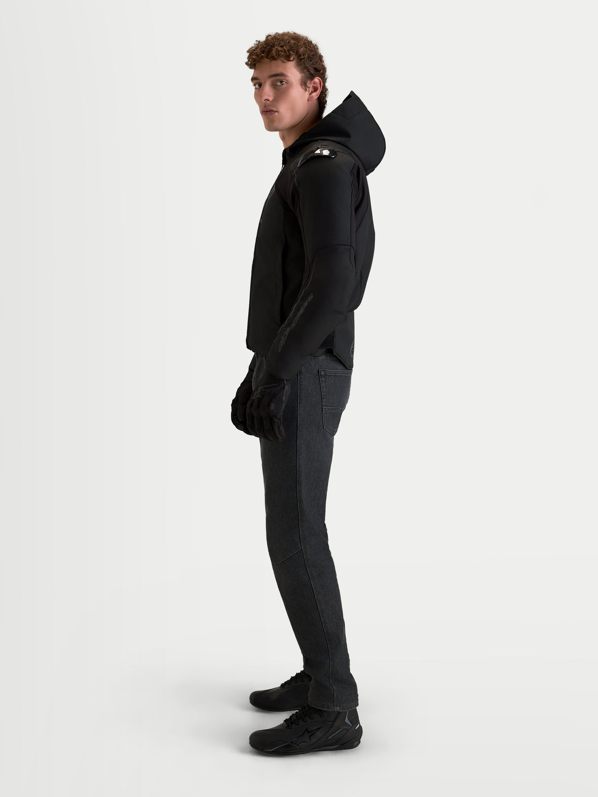Alpinestars Zaca V2 Waterproof Jacket, chaqueta de moto deportiva negra para hombre con capucha y protección integrada en los hombros, vestida por un modelo