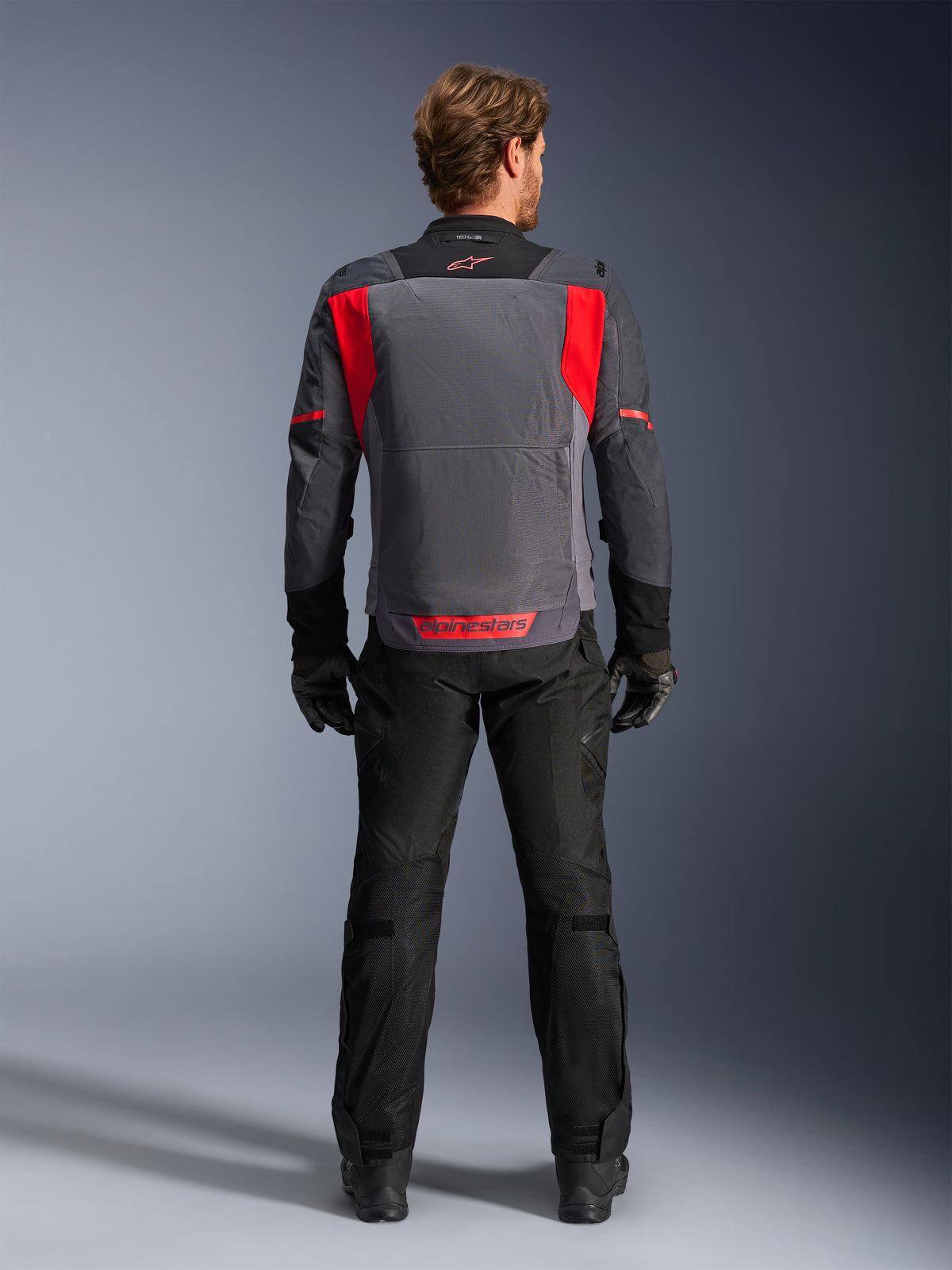 Alpinestars ST-2 Air, chaqueta de moto touring para hombre, gris y roja, vista trasera con paneles de malla.