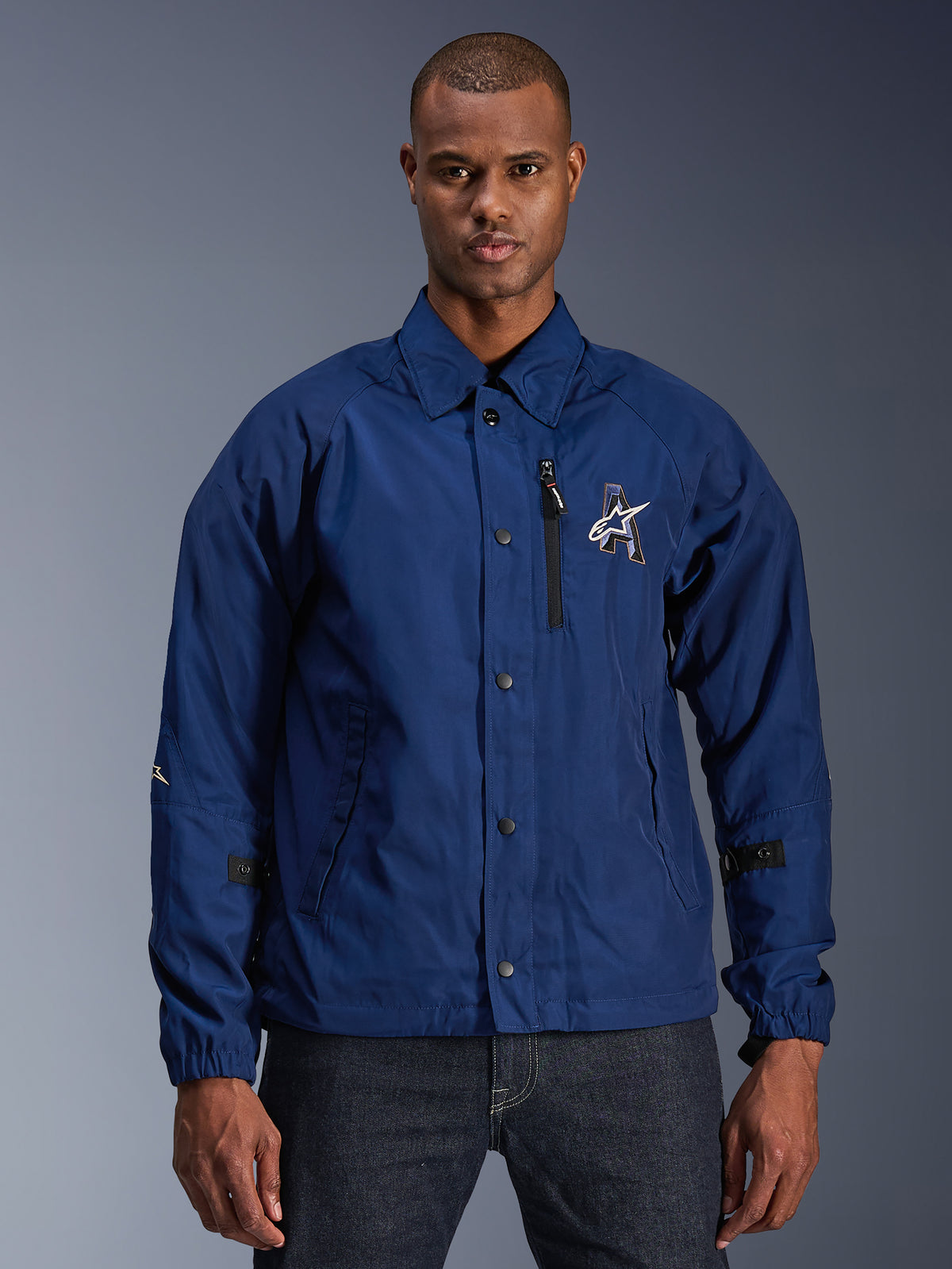 Alpinestars Revved WR Jacket, chaqueta de moto urbana para hombre, azul marino, estilo coach con cuello camisero y botones de presión frontales, bolsillo en el pecho con cremallera negra, gran logotipo bordado en 3D, pestañas ajustables en las mangas y material resistente al agua con acabado satinado