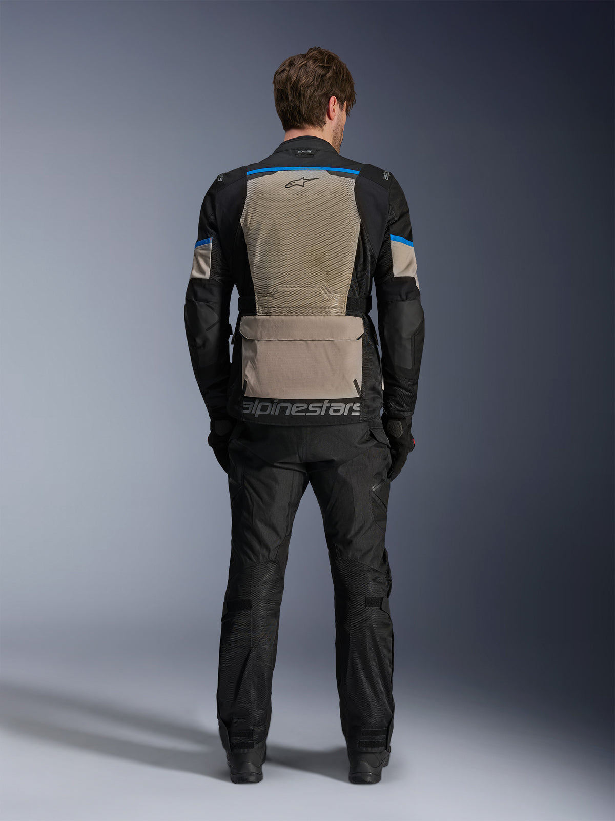 Alpinestars Andes Air Drystar® Jacket, Black Laurel Gray Bright Blue, rear view showing extensive mesh ventilation panel, large lower back storage pocket with Alpinestars branding, technical motorcycle touring jacket worn with matching trousers.