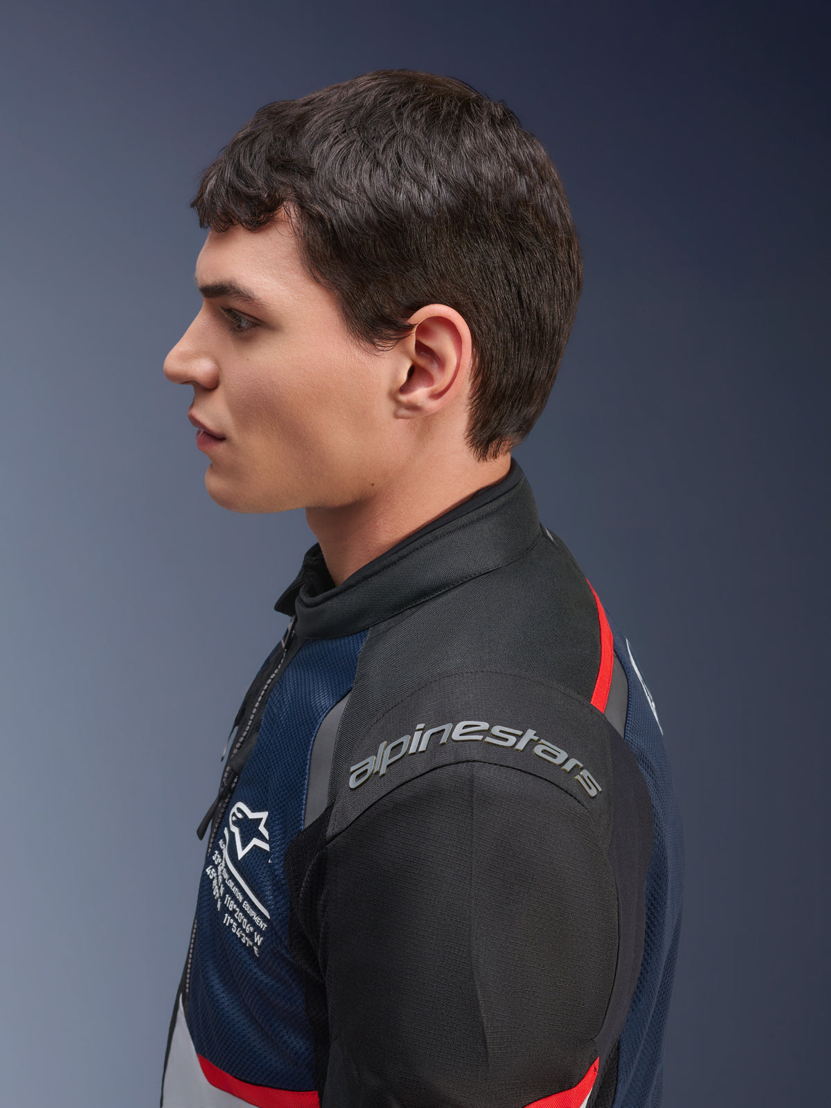 Chaqueta Alpinestars Andes Air Drystar®, combinación de colores Deep Blue Black Ice Gray, perfil lateral de un modelo masculino usando la chaqueta textil de malla, con el logotipo de Alpinestars en el hombro y detalles en rojo, equipamiento de touring para dos estaciones