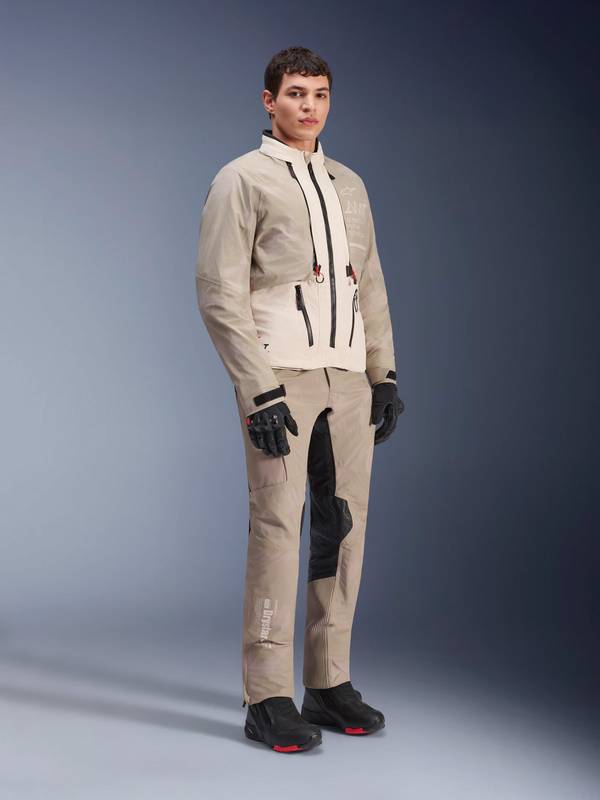 Pantalones Alpinestars AMT-10LAB Drystar® XF y chaqueta a juego, equipamiento de aventura en Aluminum Camo, conjunto completo con guantes y botas negros, con logotipos técnicos y paneles protectores modulares, foto de estilo de vida en estudio